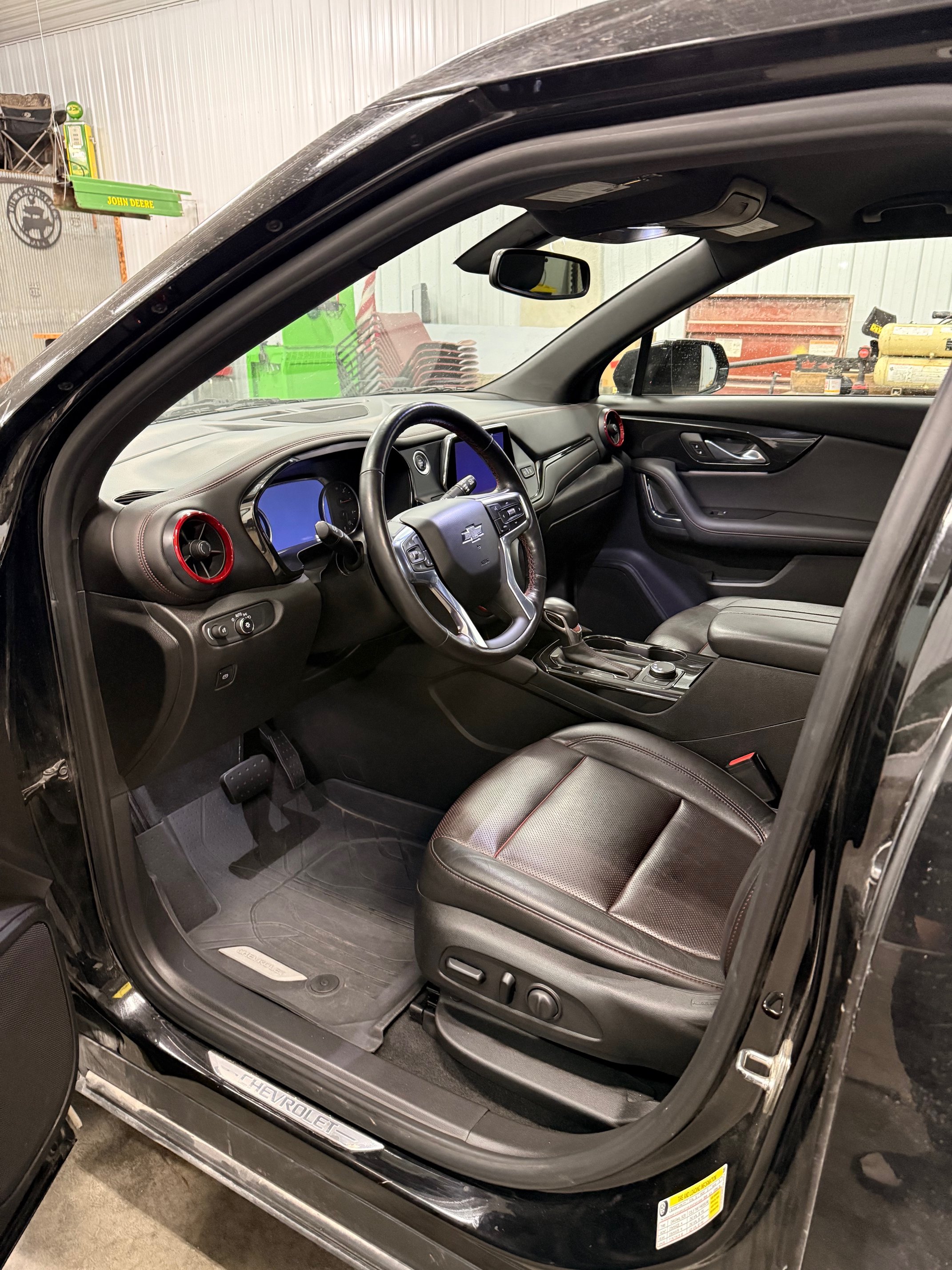 Interior of a black Chevrolet vehicle showing the driver's seat, steering wheel, dashboard, and center console.