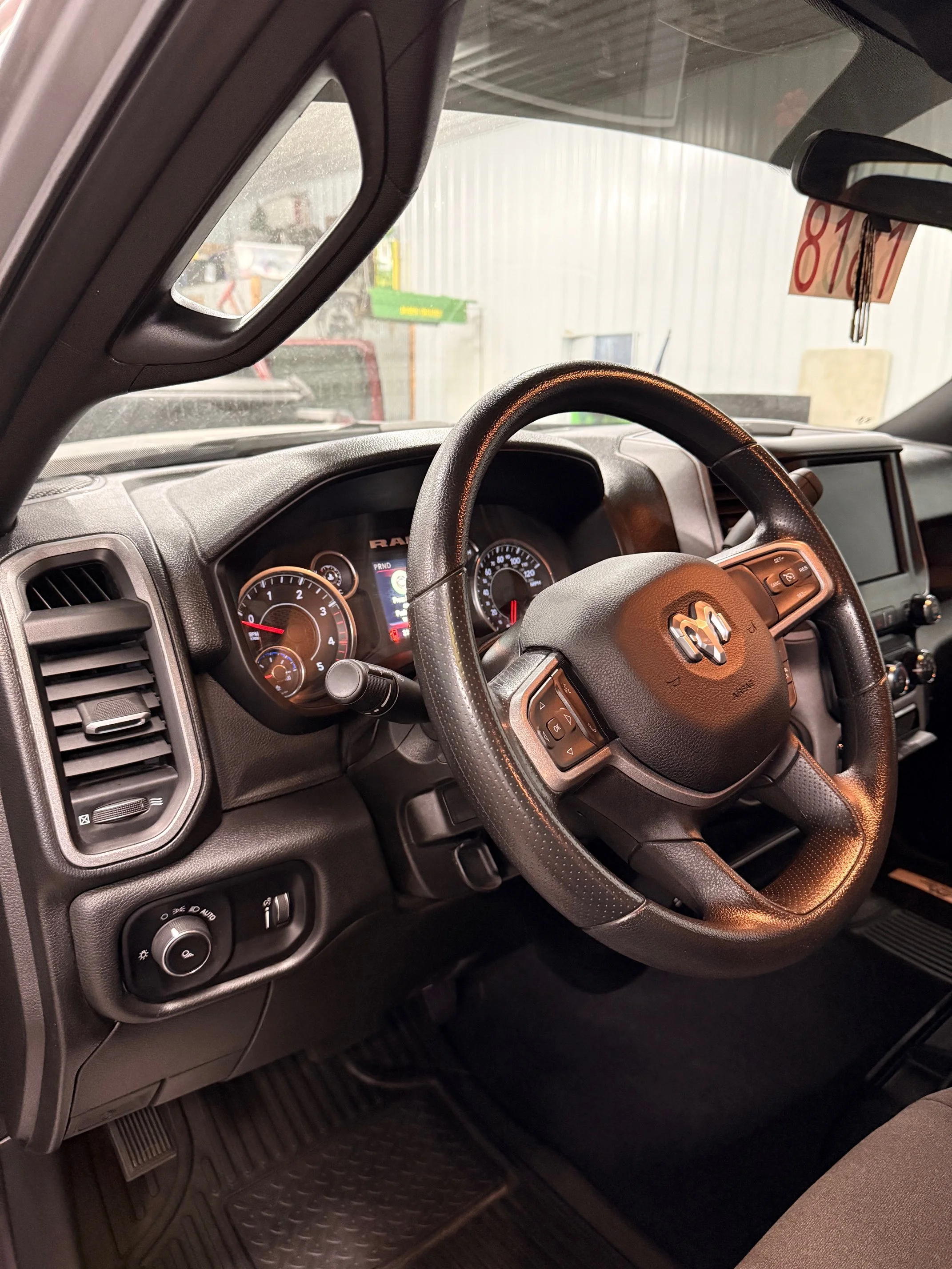 The interior of a vehicle showing the steering wheel, dashboard, gauges, and controls.