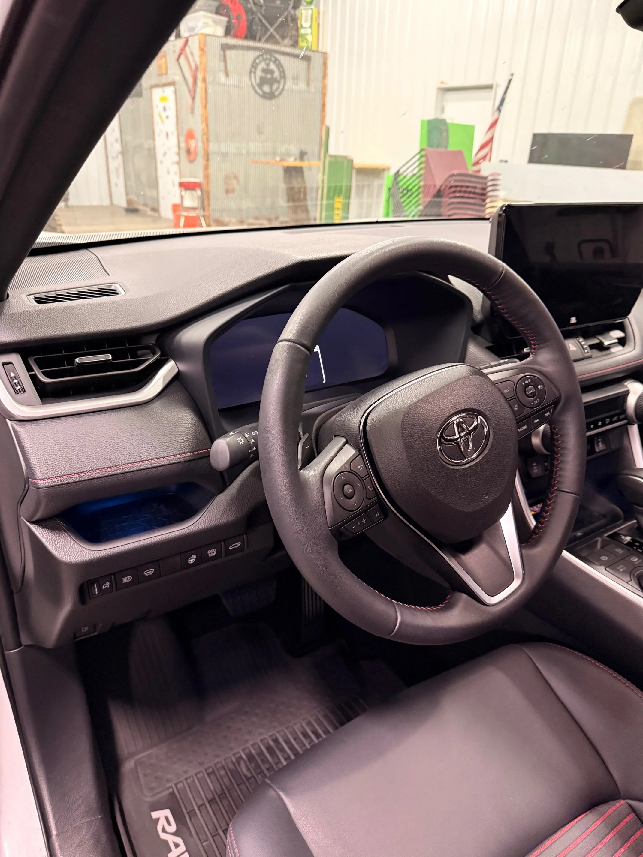 Interior of a Toyota RAV4 showing the steering wheel, dashboard, and part of the front seat inside a vehicle.