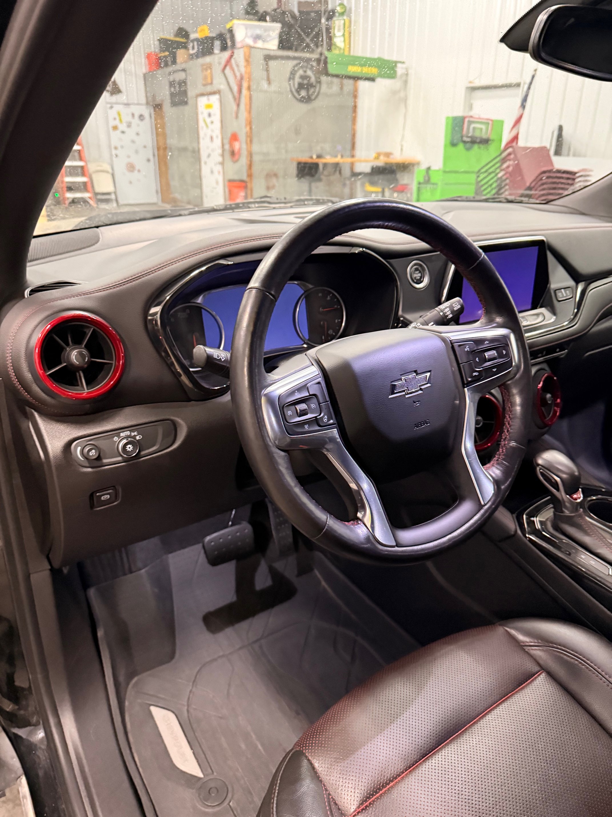 The interior of a Chevrolet vehicle showing the steering wheel, dashboard, and center console with two large screens and red accents on the air vents.