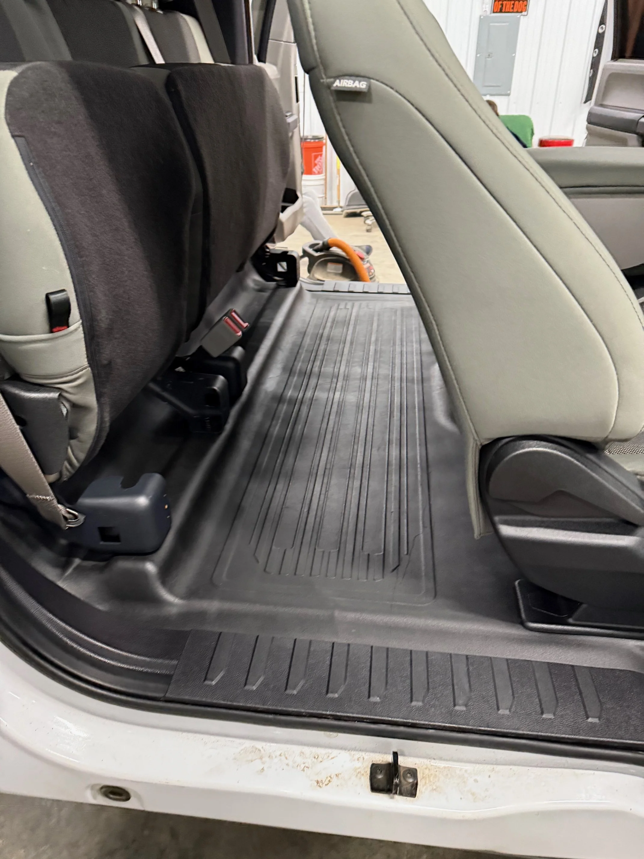 Back row of a vehicle interior with a removable flat floor panel, showing the cargo area with uncovered metal floor.