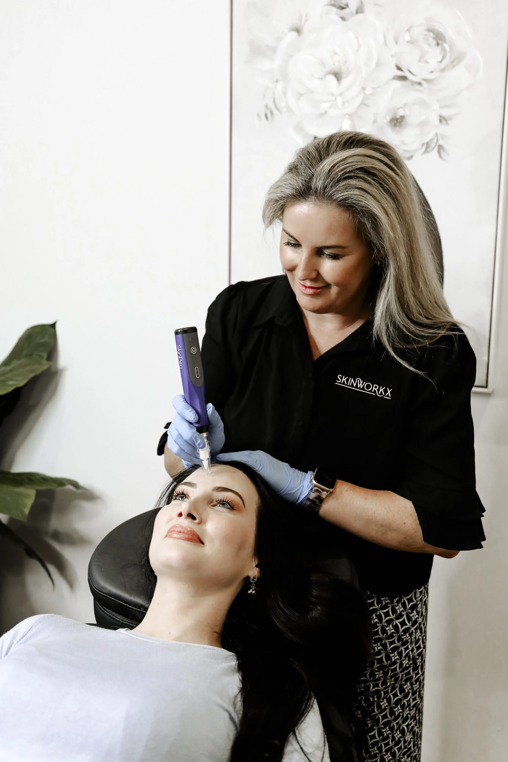 A woman receiving a cosmetic treatment from another woman in a skincare clinic.