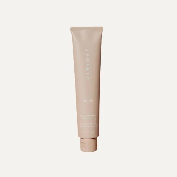 A beige tube of sunscreen with SPF 50+ from AIRYDAY, with the label 'Golden Glow' on a plain light background.