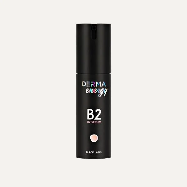 A black bottle of DERMA energy B2 serum with a pinkish-brown dot on the label, against a plain light background.