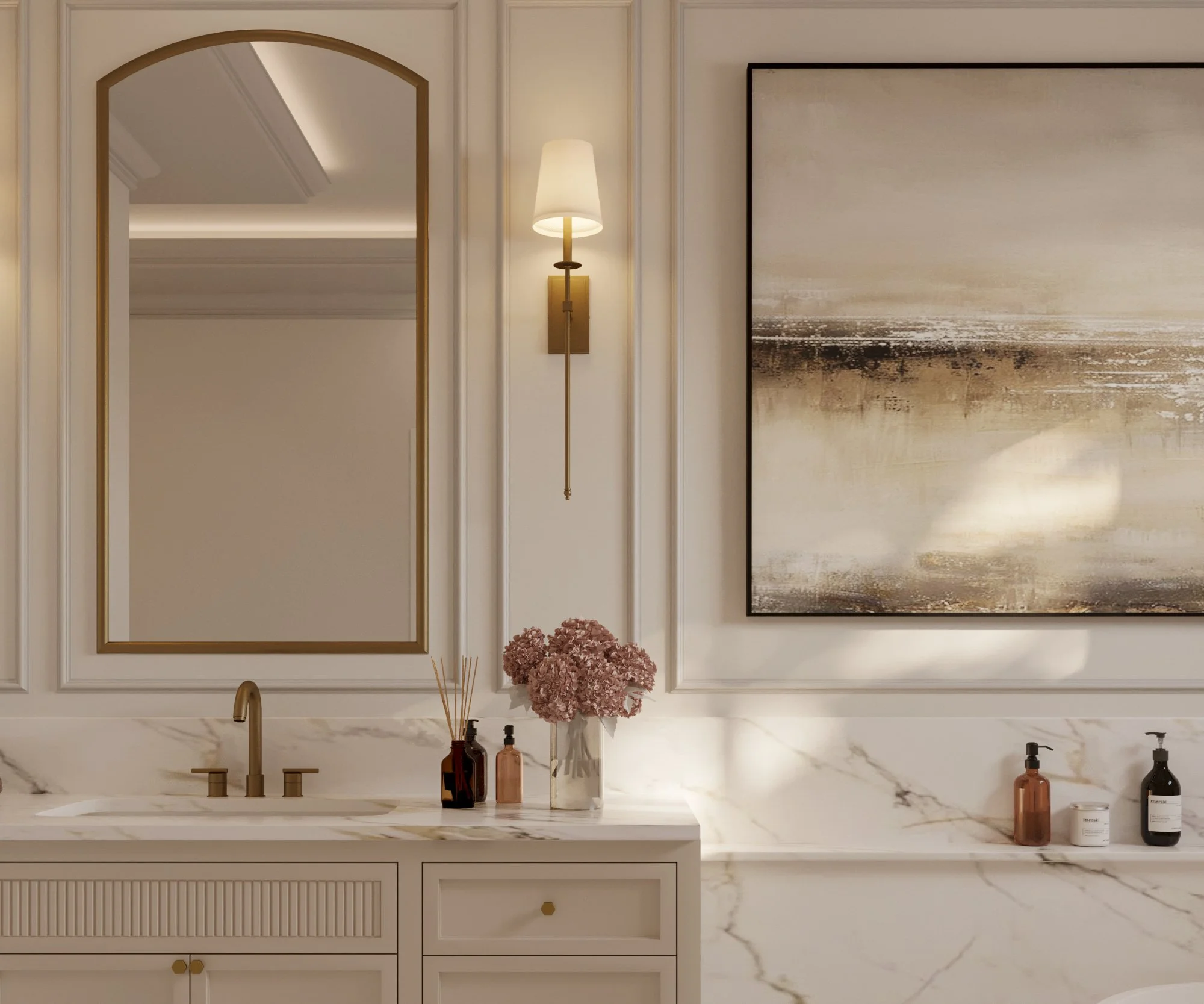 This is a bathroom interior with a white marble countertop, a modern brass faucet, and a large abstract artwork on the wall. There are bottles of skincare products, a vase with pink flowers, and a mirror with a golden frame on the wall. A wall-mounte