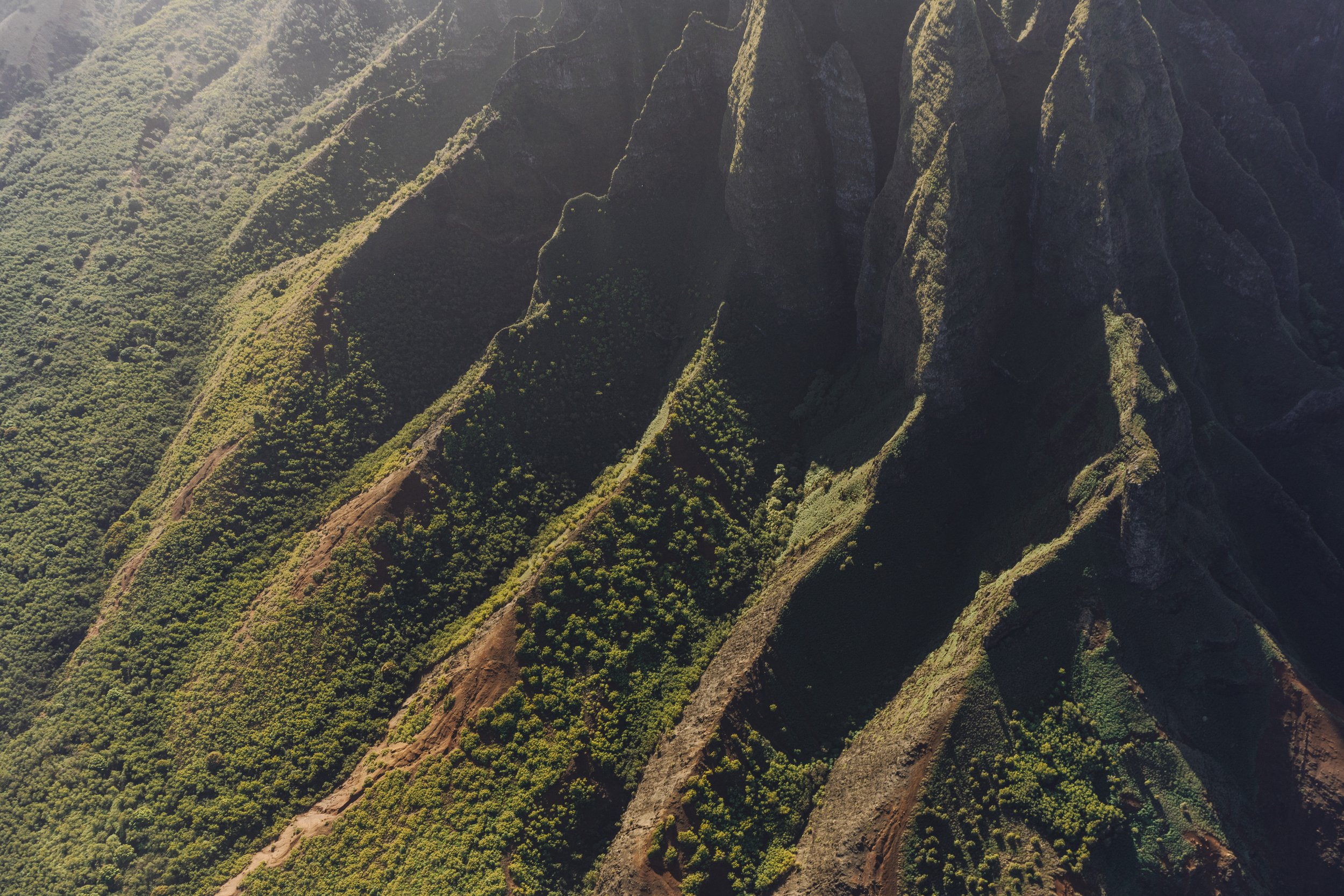 Aerial view of lush green mountains with steep slopes and rugged peaks