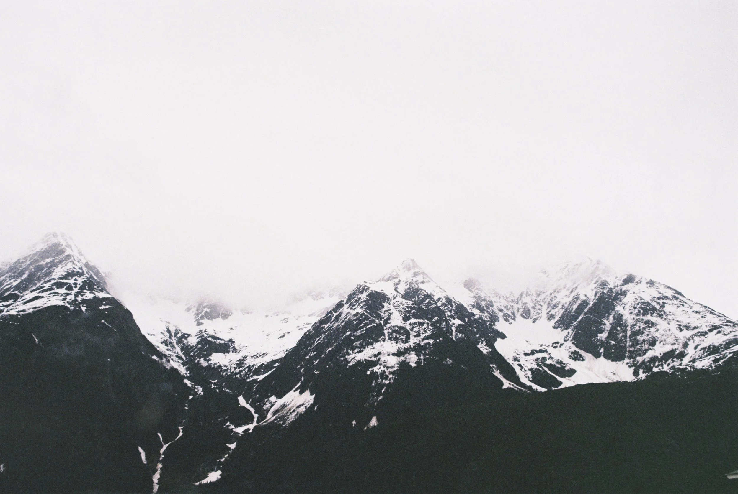 Snow-covered mountain peaks under a cloudy sky.