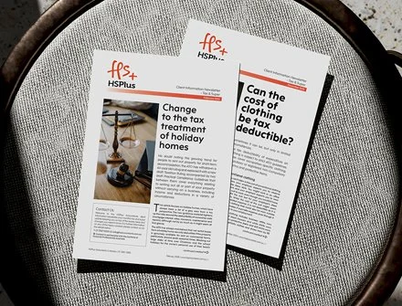 Two printed newsletters or flyers on a gray fabric surface, with the headline 'Change to the tax treatment of holiday homes' on one of them.