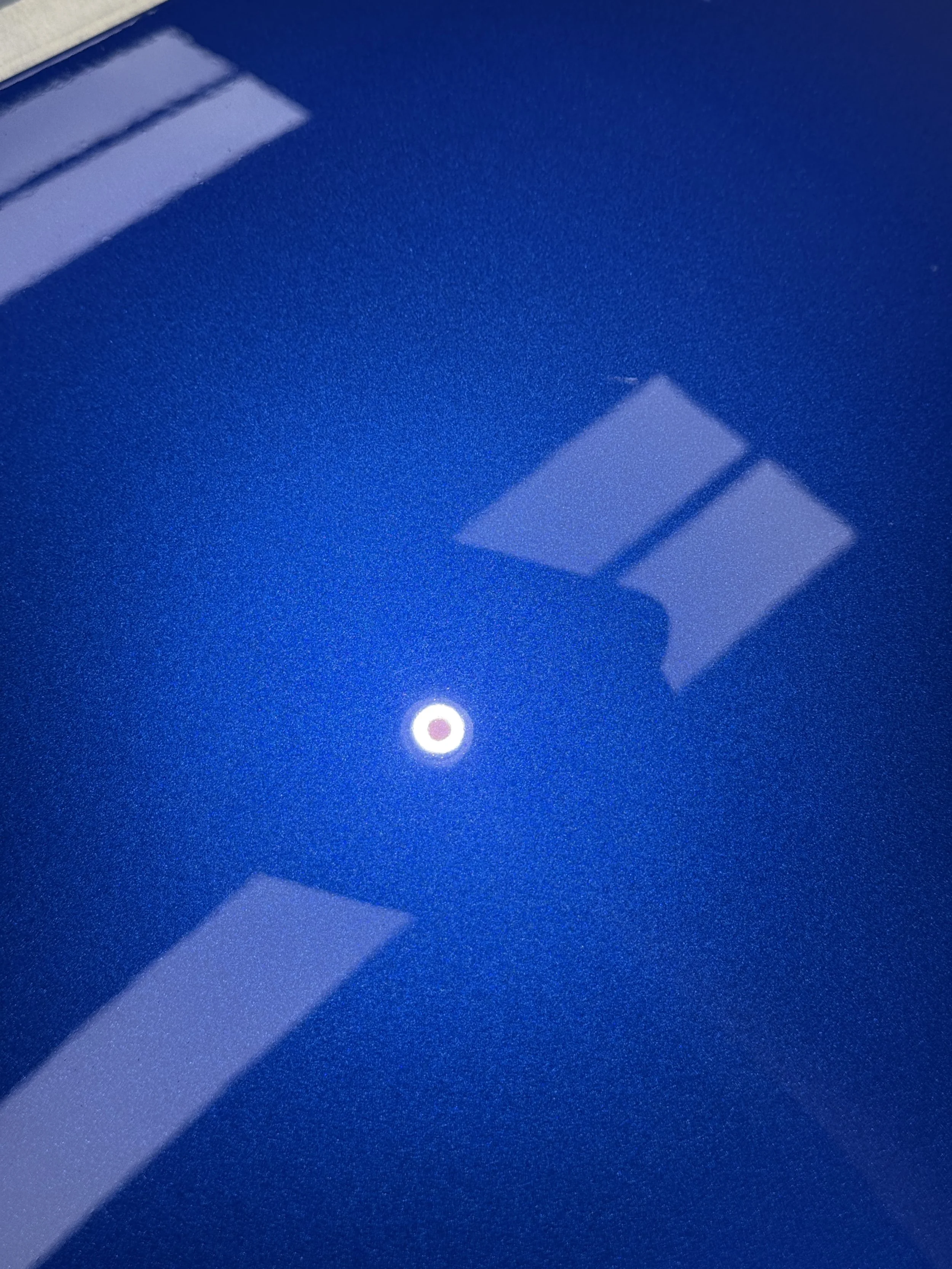 Blue metallic paint after polishing, showing a clearer inspection light reflection and visibly reduced swirl marks.