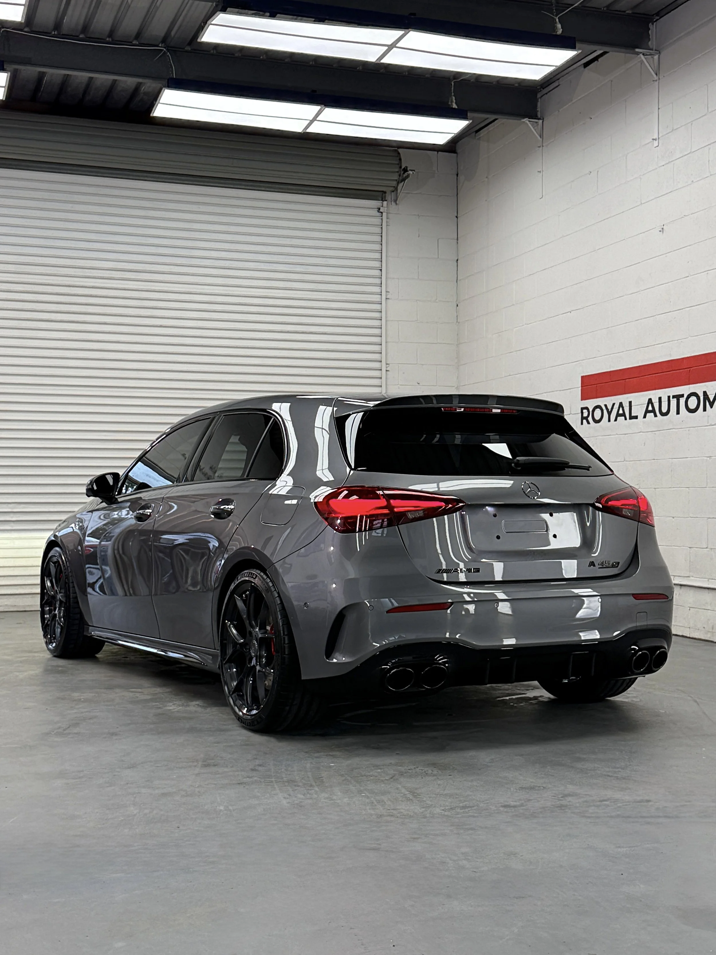 Rear three-quarter view of the grey Mercedes-AMG A45 S showing reflections across the finished paintwork.