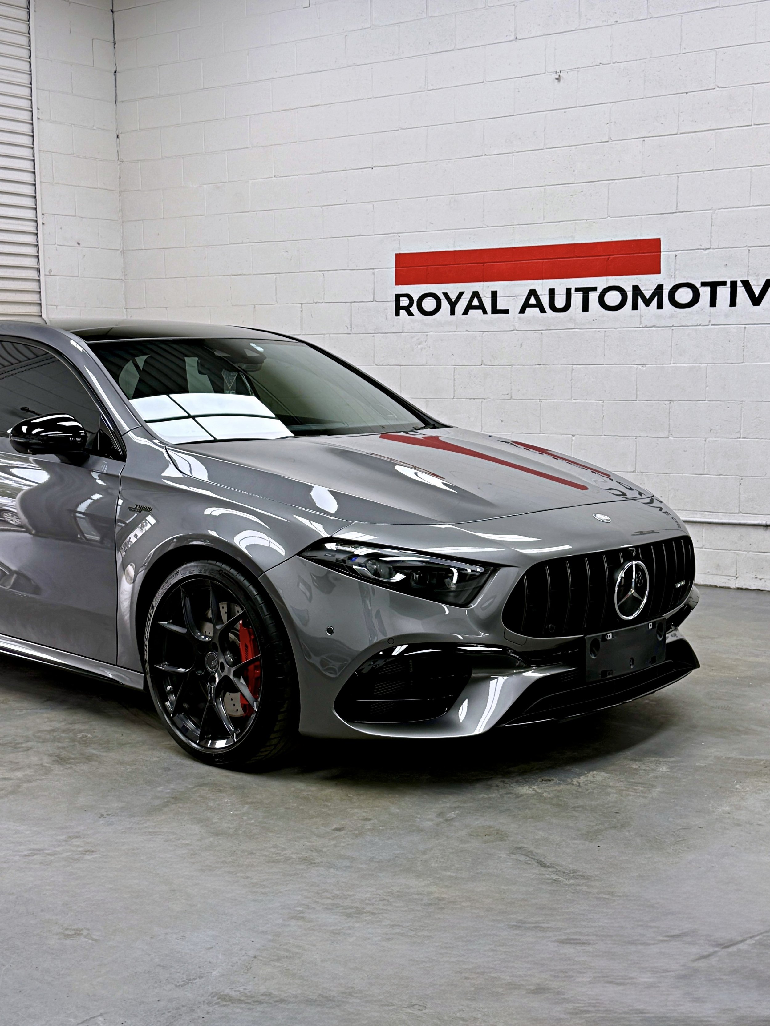 front three-quarter view of the grey Mercedes-AMG A45 S showing reflections across the finished paintwork.