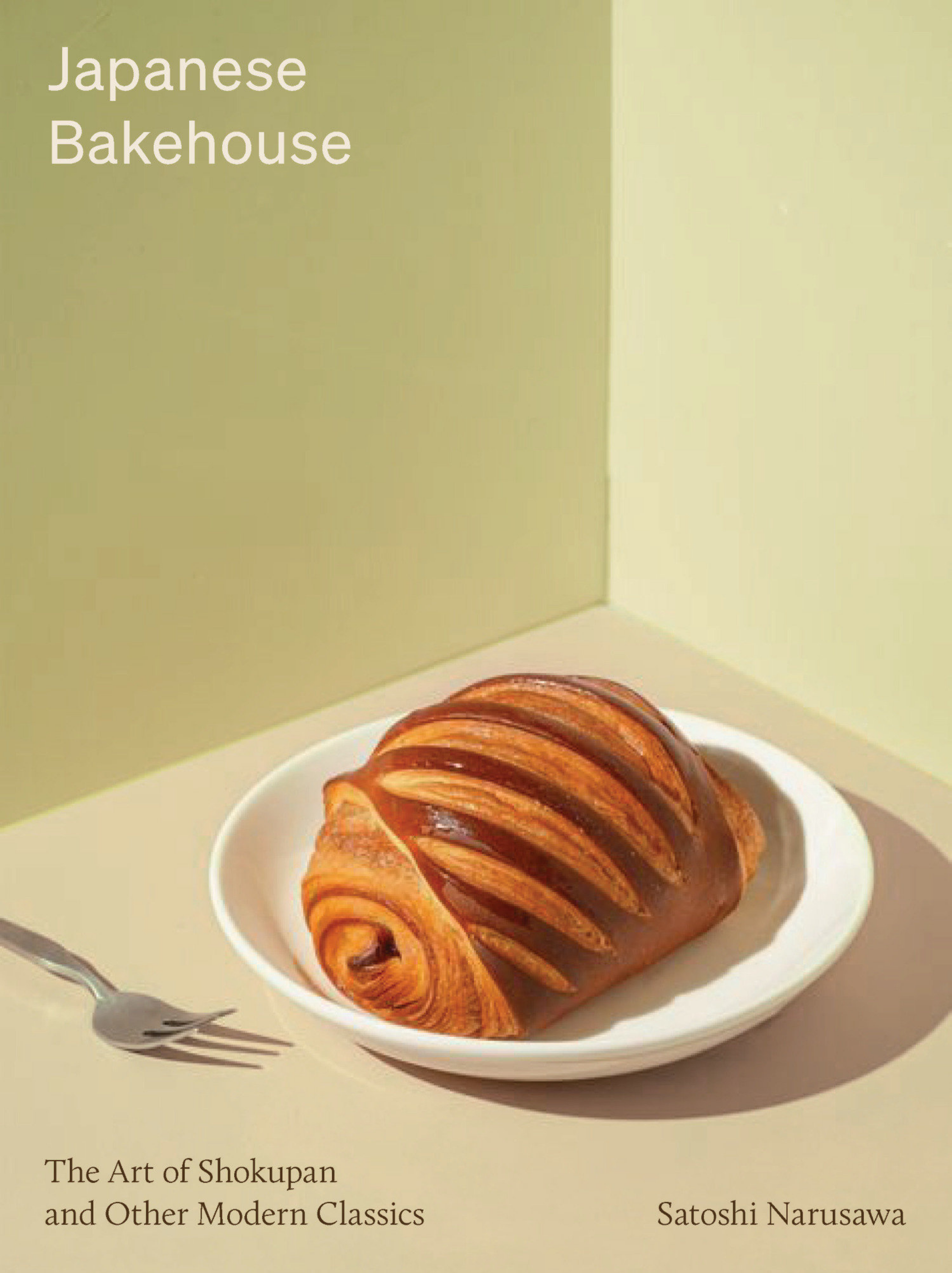 A cover of a book titled The Art of Shokupan and Other Modern Classics by Satoshi Narusawa, featuring a photograph of a sliced, golden-brown, spiral-shaped bread with a glossy crust in a white bowl on a green and beige background.