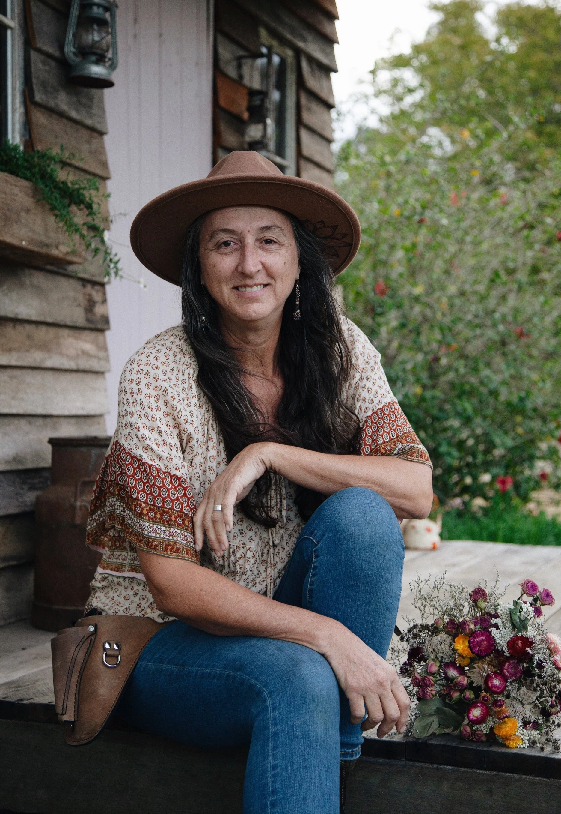 Angela, owner of Wild Acres Flower Farm, sitting at the Flower Hut holding a bunch of homegrown dried flowers.