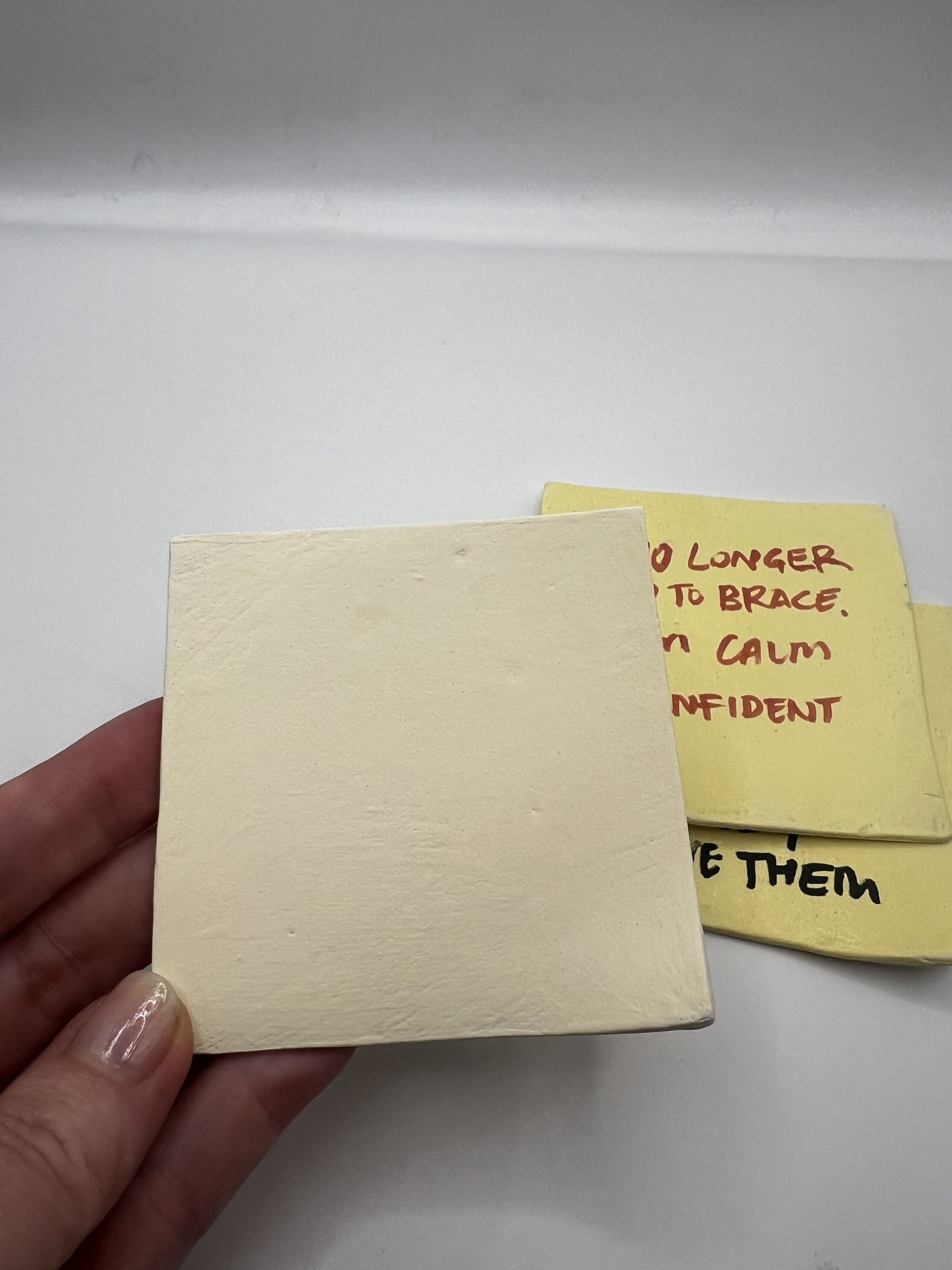 Hand-sculpted ceramic post-it note with custom wording, glazed and fired