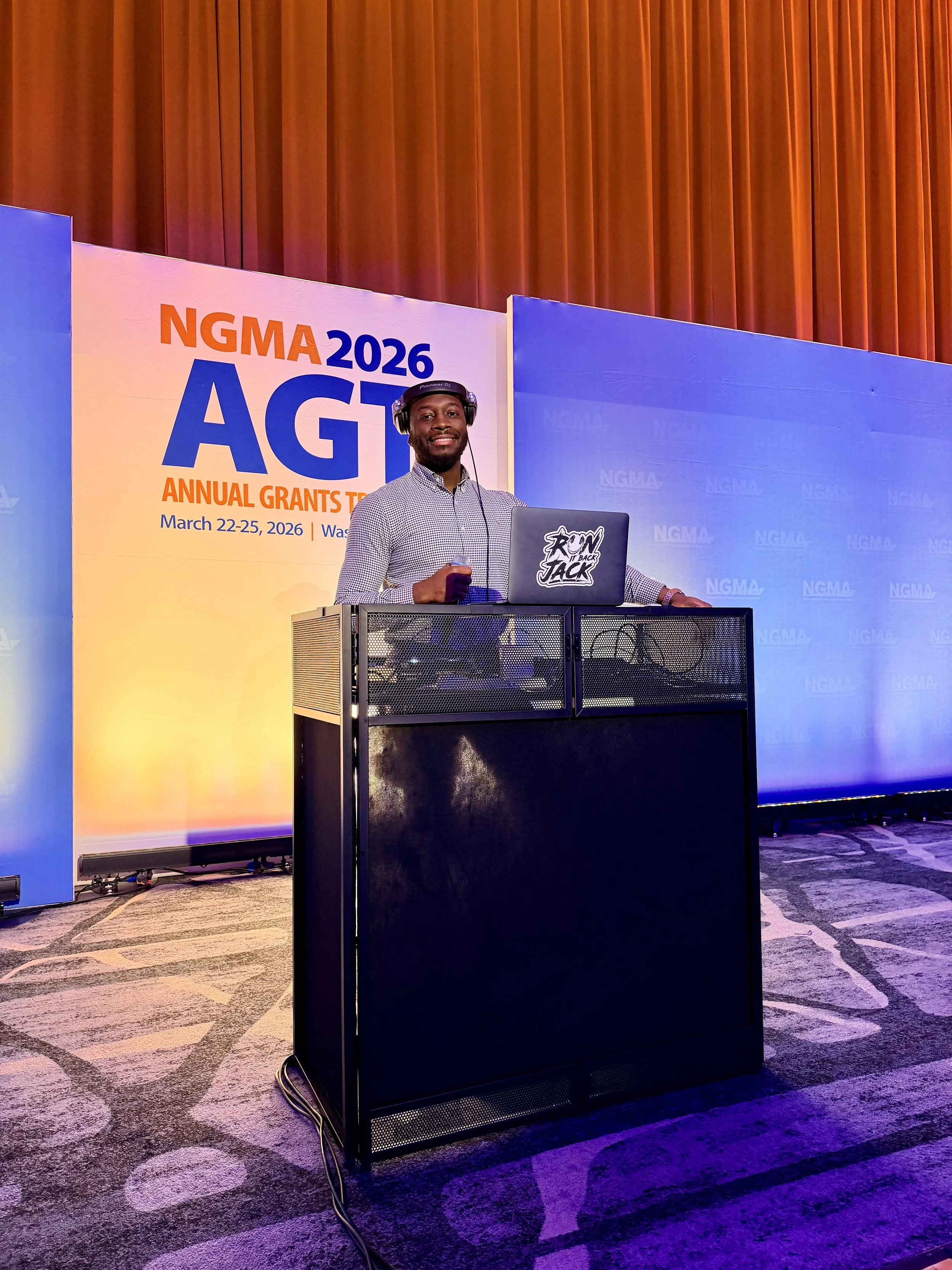 A man with headphones standing behind a DJ booth at the NGMA 2026 AGT Annual Grants Training event held March 22-25, 2026, in Washington, D.C.