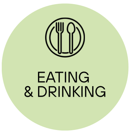 Symbol of a plate with a fork and spoon above the words "Eating & Drinking" on a light green circular background.
