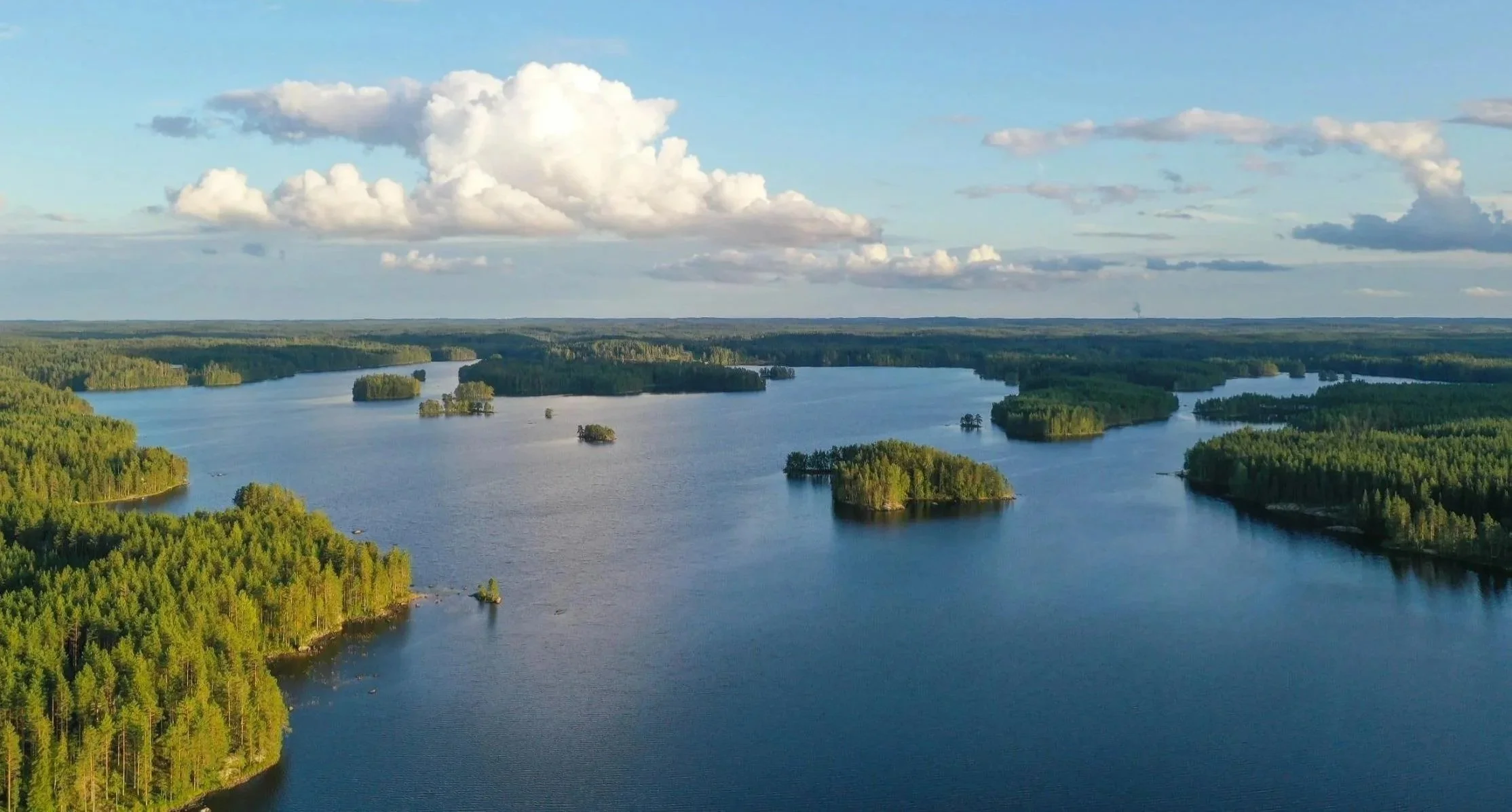 Aerial photo of Lake Ilmajärvi in the summer with blue water, small islands and evergreen forests