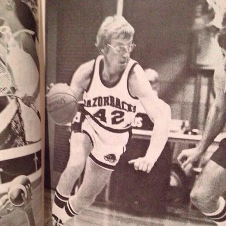 Black and white photo of a female basketball player wearing a Washington Huskies jersey with the number 42, dribbling a basketball.