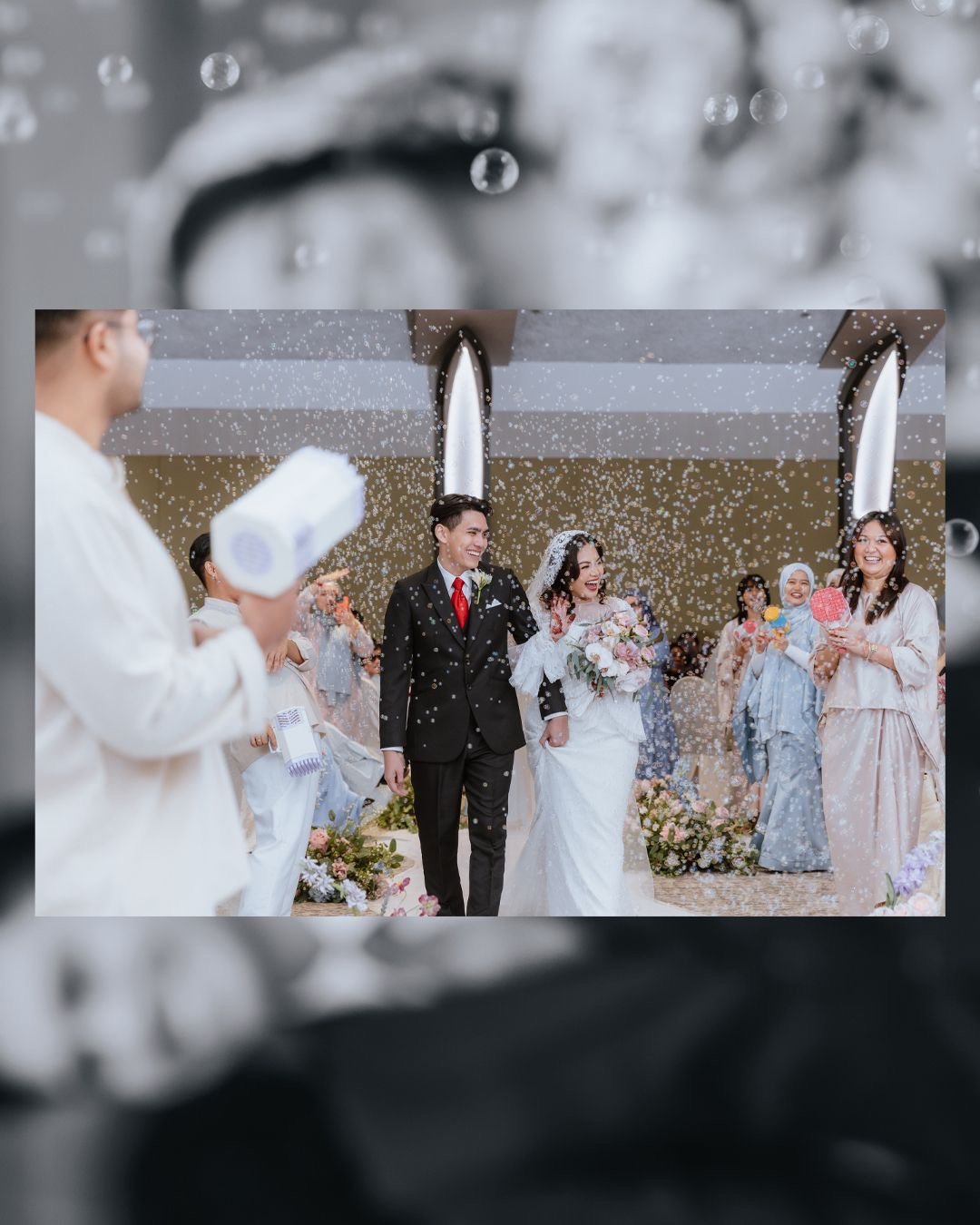 A wedding celebration with a bride and groom walking down the aisle, surrounded by guests, as confetti is falling from above.