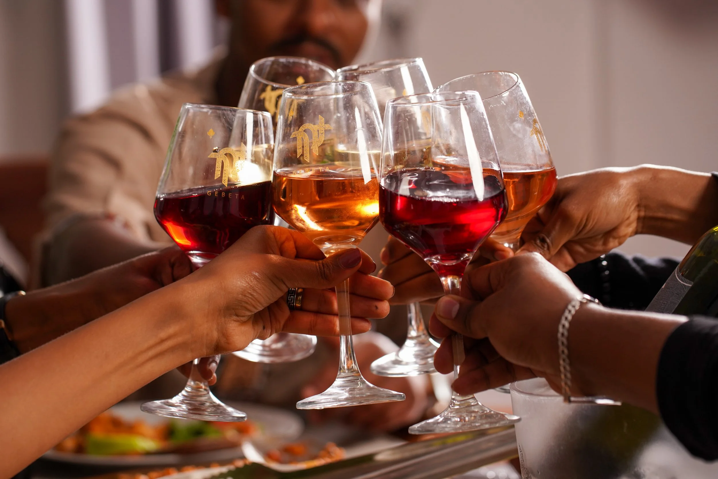 People clinking glasses with rosé and red wine in a celebration toast.
