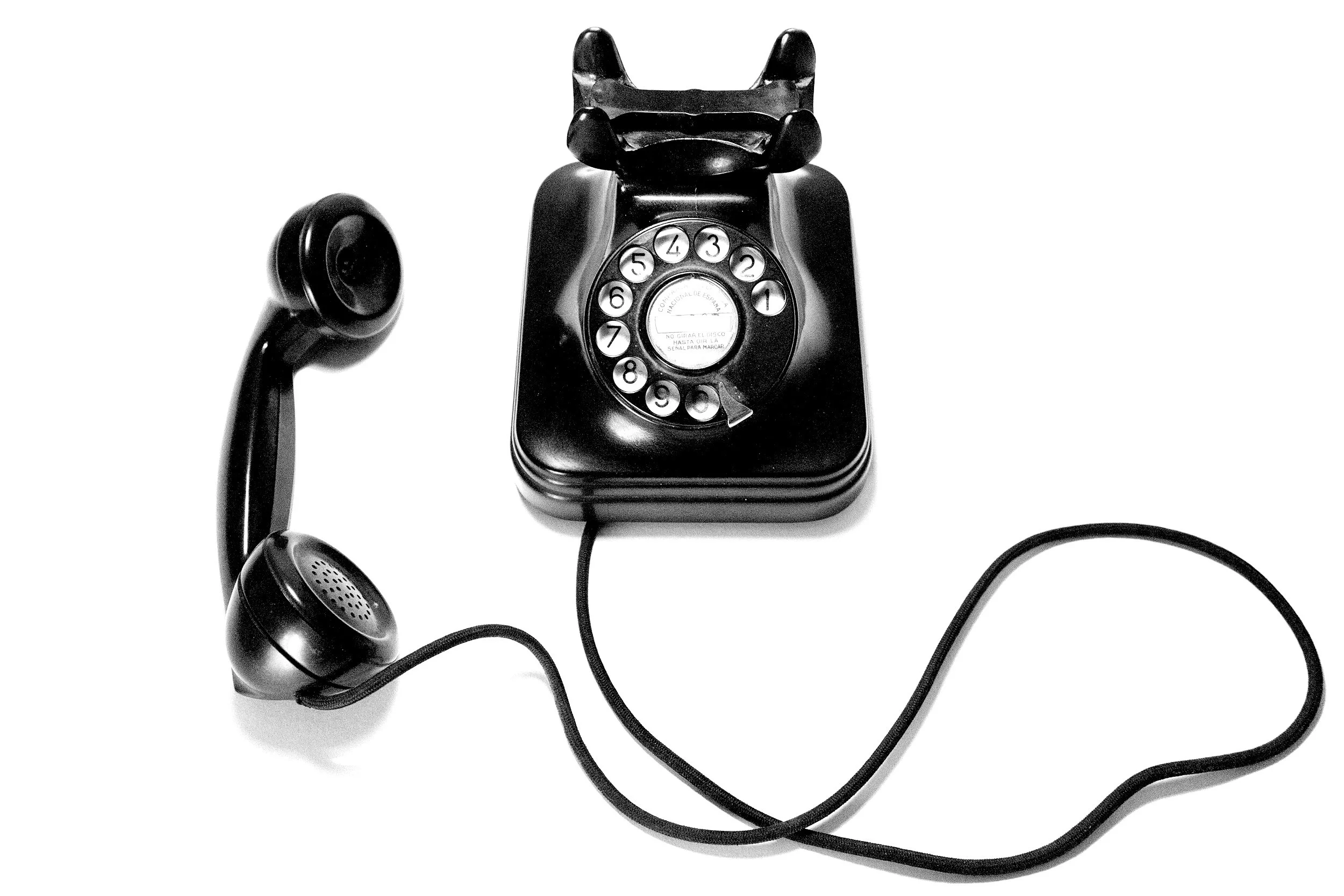 Black rotary telephone with a handset resting on the hook and a coiled cord connecting the handset to the base.