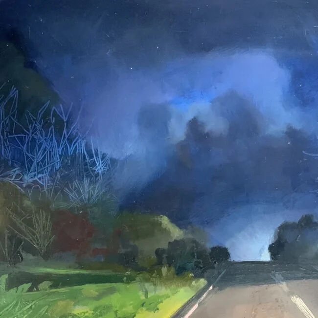 Nighttime landscape with a dirt road, trees, and a cloudy sky illuminated in blue and green hues.