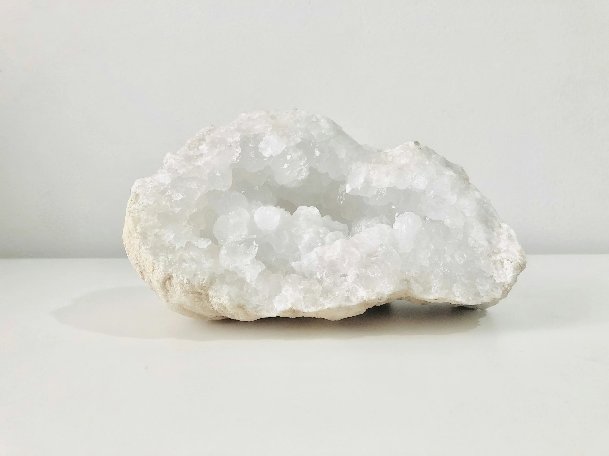A white, irregularly shaped crystal with a rough surface, placed against a plain white background.