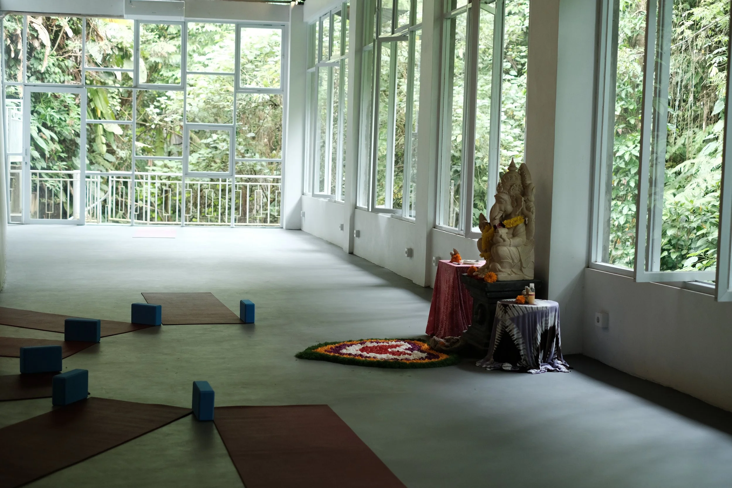 An enclosed event space with large windows overlooking greenery, with air conditioning and toilet.