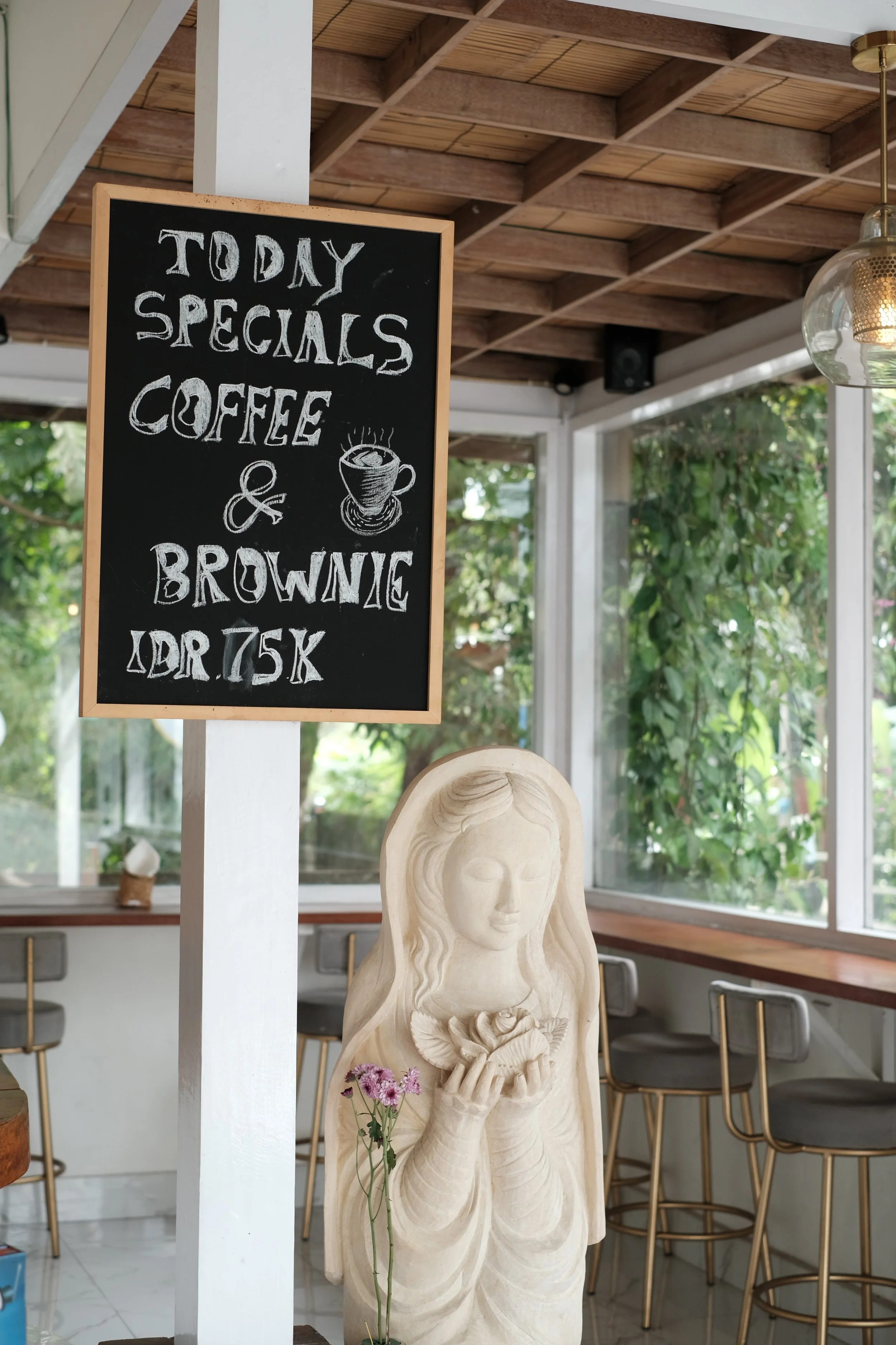 A blackboard sign beside it reads 'Today Specials Coffee & Brownie', a cozy cafe with large windows and natural light which opens to a generous outdoor seating area.