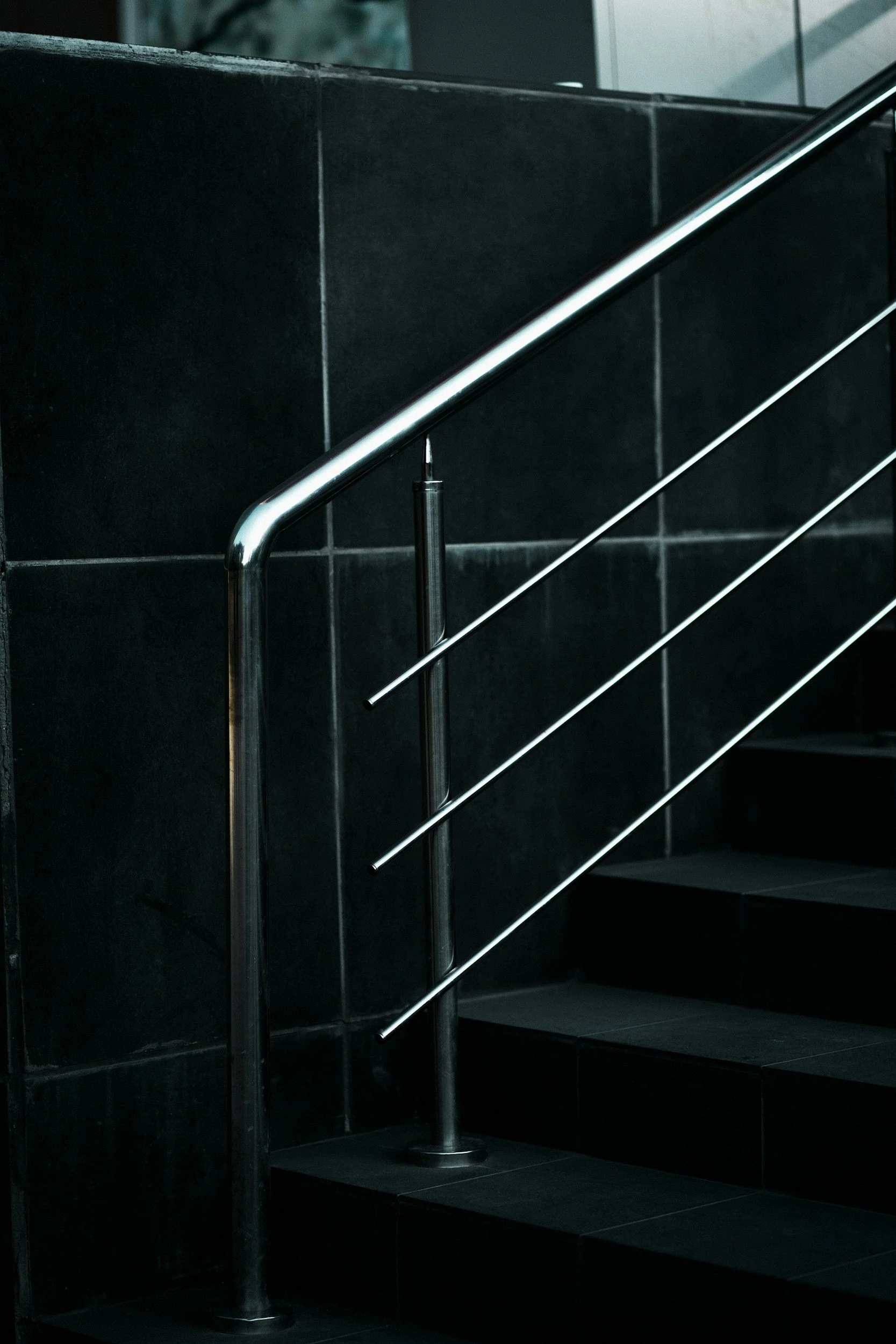 A staircase with black tiled steps and metal handrails in a modern indoor setting.