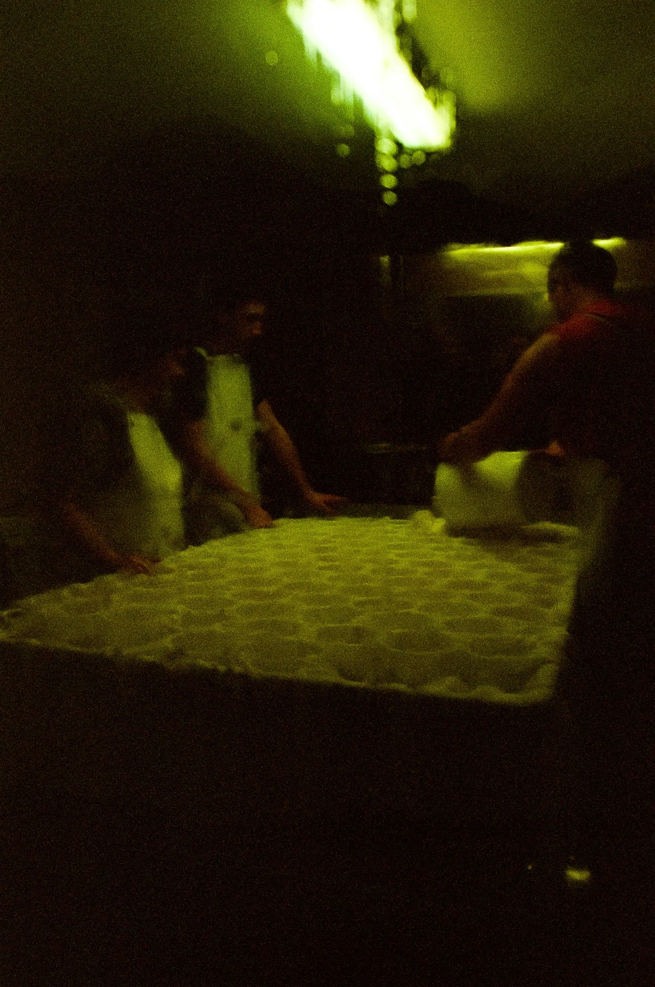 Trois personnes en train de mouler des fromages Reblochon, dans l'atelier de fabrication de leur ferme en Savoie, au petit matin. Photographie argentique.