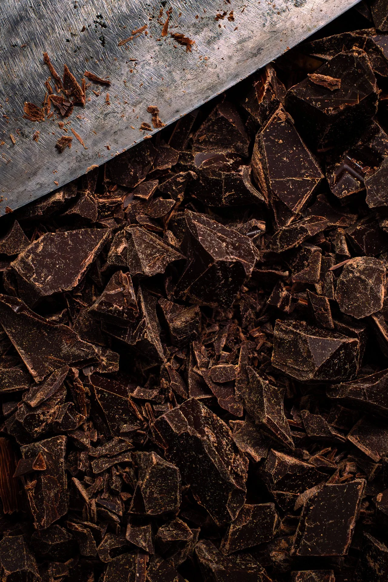 Texture d'éclats de chocolat noir, avec un couteau posé au-dessus d'eux,