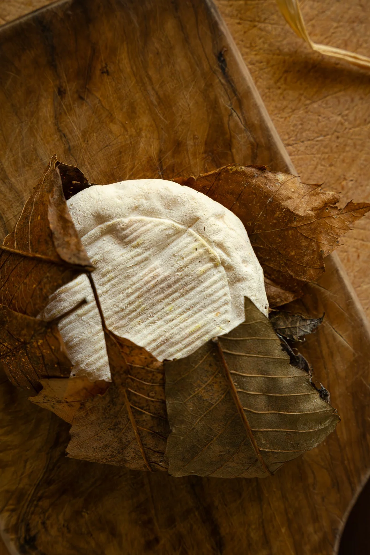 Fromage Banon AOP, déballé de ses feuilles de châtaignier et posé sur une planche en bois. Vue du dessus.