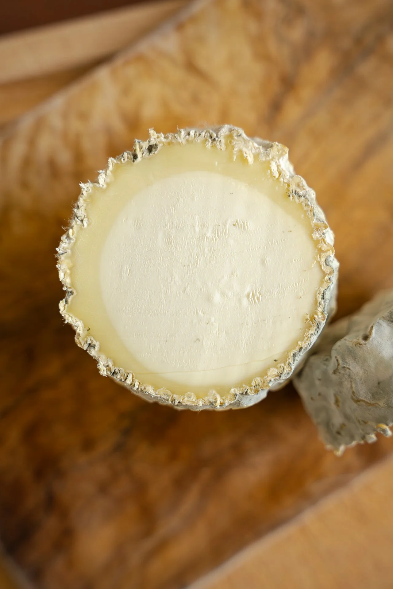 Gros plan du Clacbitou, un fromage de chèvre semblable à un Charolais, tranché pour révéler son cœur à la texture fine et soyeuse, et au contour crémeux.