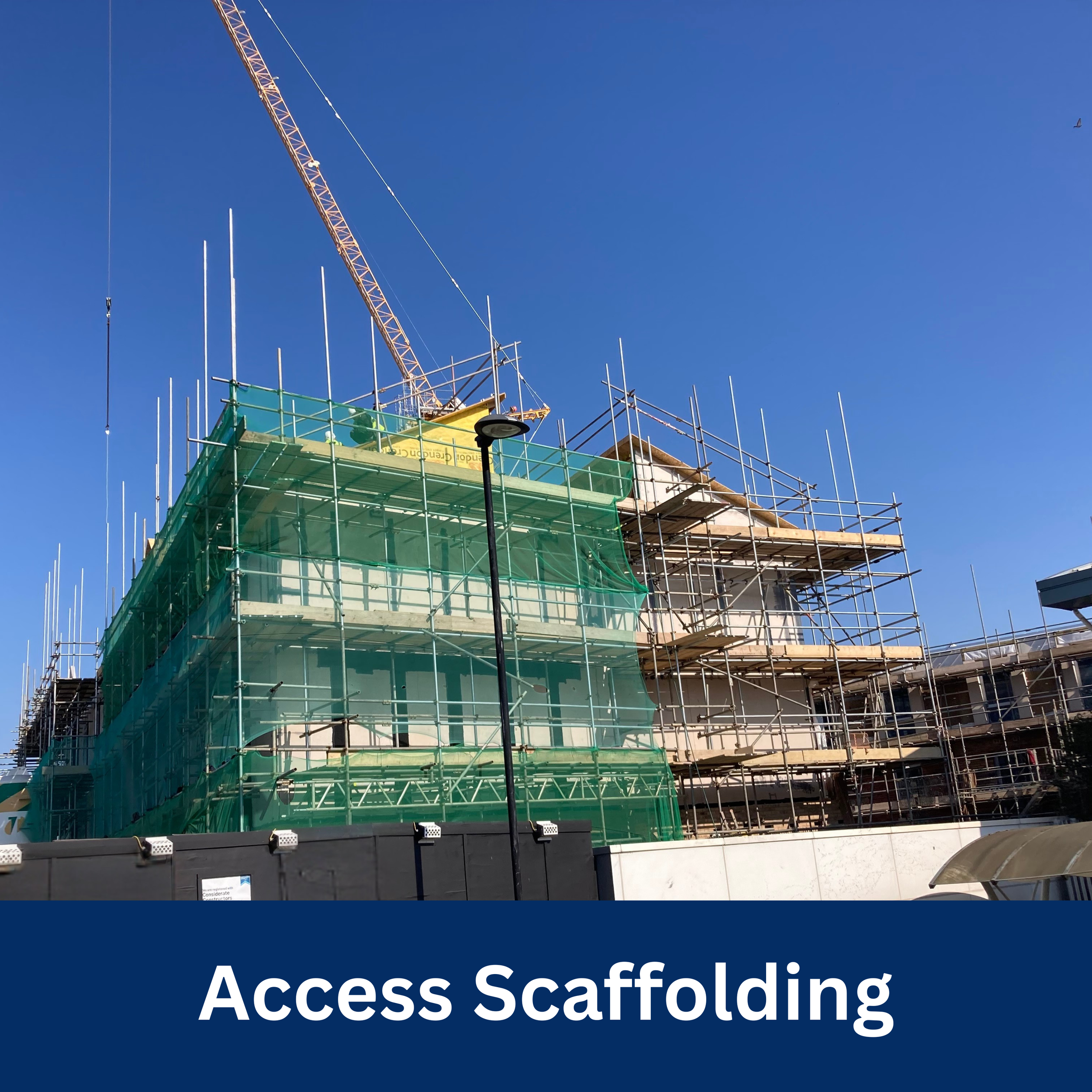 Construction site with scaffolding around a building and a crane in the background, under a blue sky, labeled Access Scaffolding.