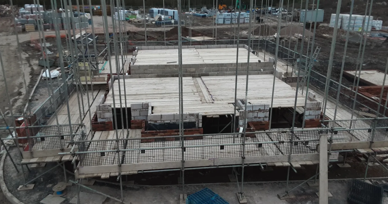 Construction site with scaffolding and partially built brick walls for a building structure.