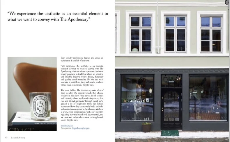 To-etasjes bygning med store vinduer på gateplan og mindre vinduer på øverste etasje. Inne i bygningen er det synlige hyller og opplyste områder, noe som tyder på at det er en butikk eller kafé. Silje Chantel