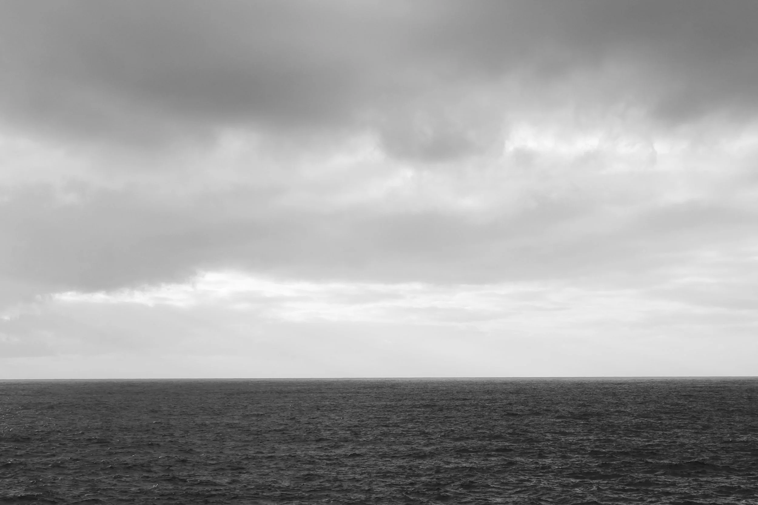 Det er et svart-hvitt bilde av havet med en mørk himmel med skyer. Silje Chantel