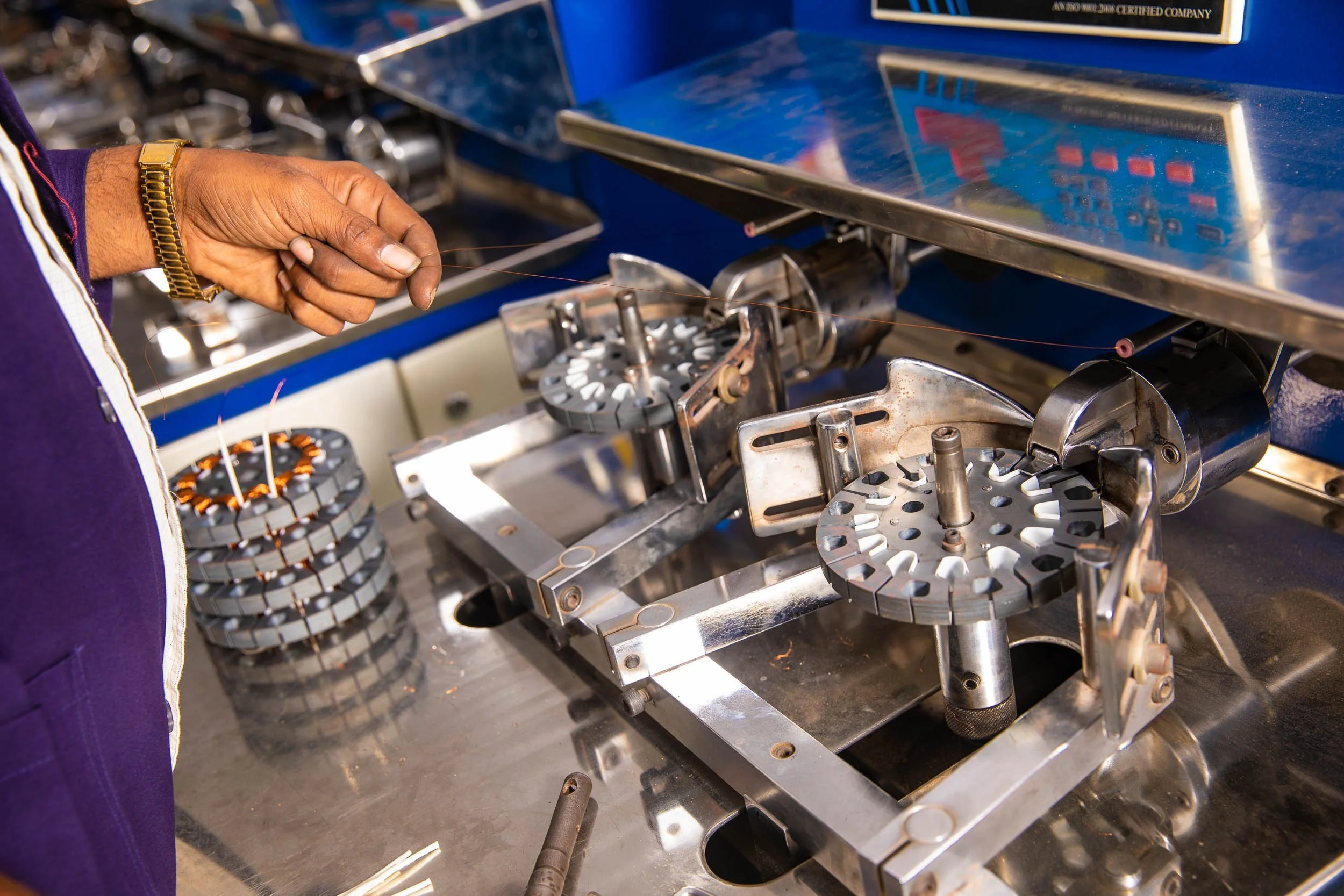 Close-up industrial photography of complex automated metal machinery with blue structural components on a manufacturing production line