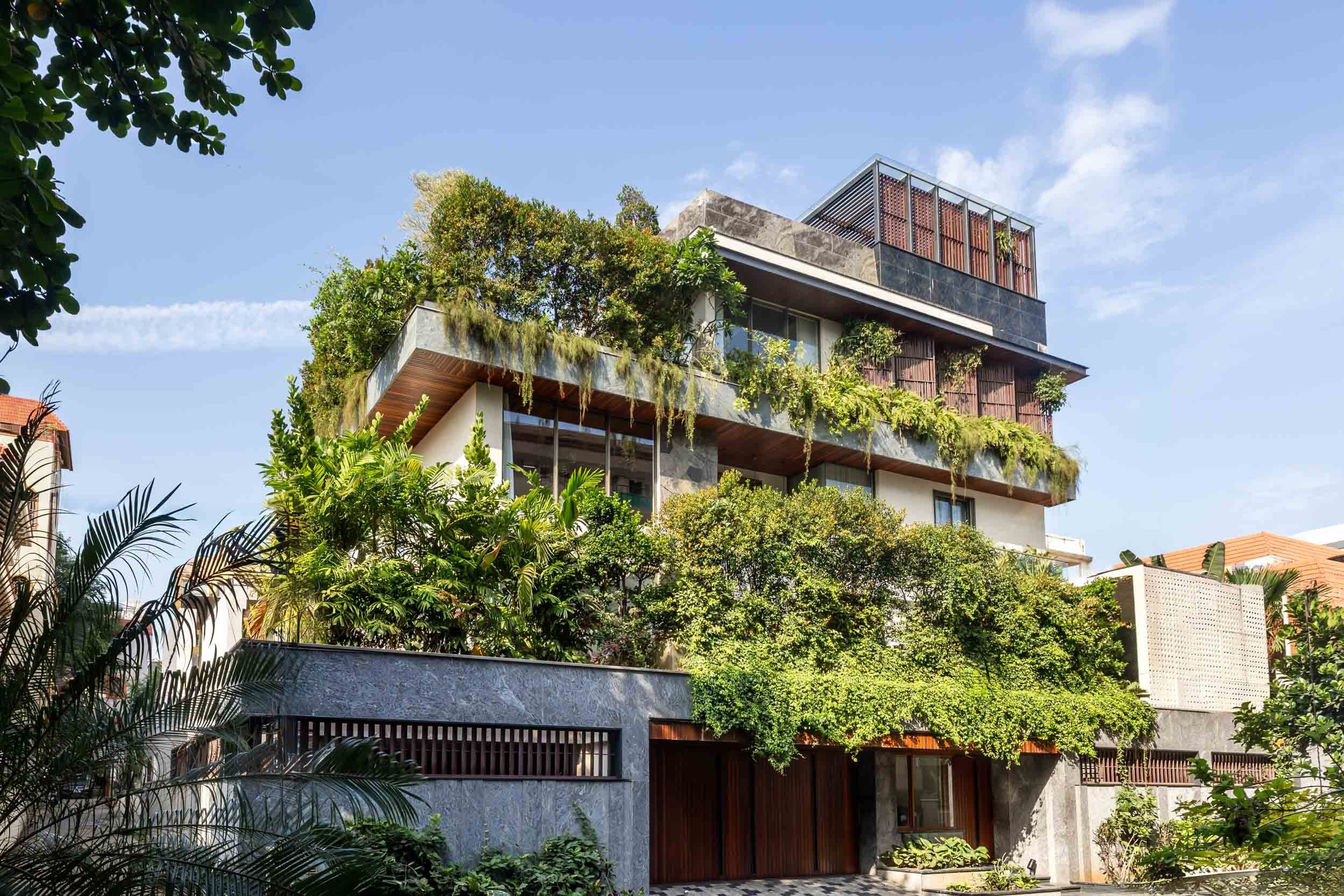 Professional exterior architectural photography of a modern multi-story residential home, highlighting a stunning biophilic design with lush hanging gardens and warm wooden accents