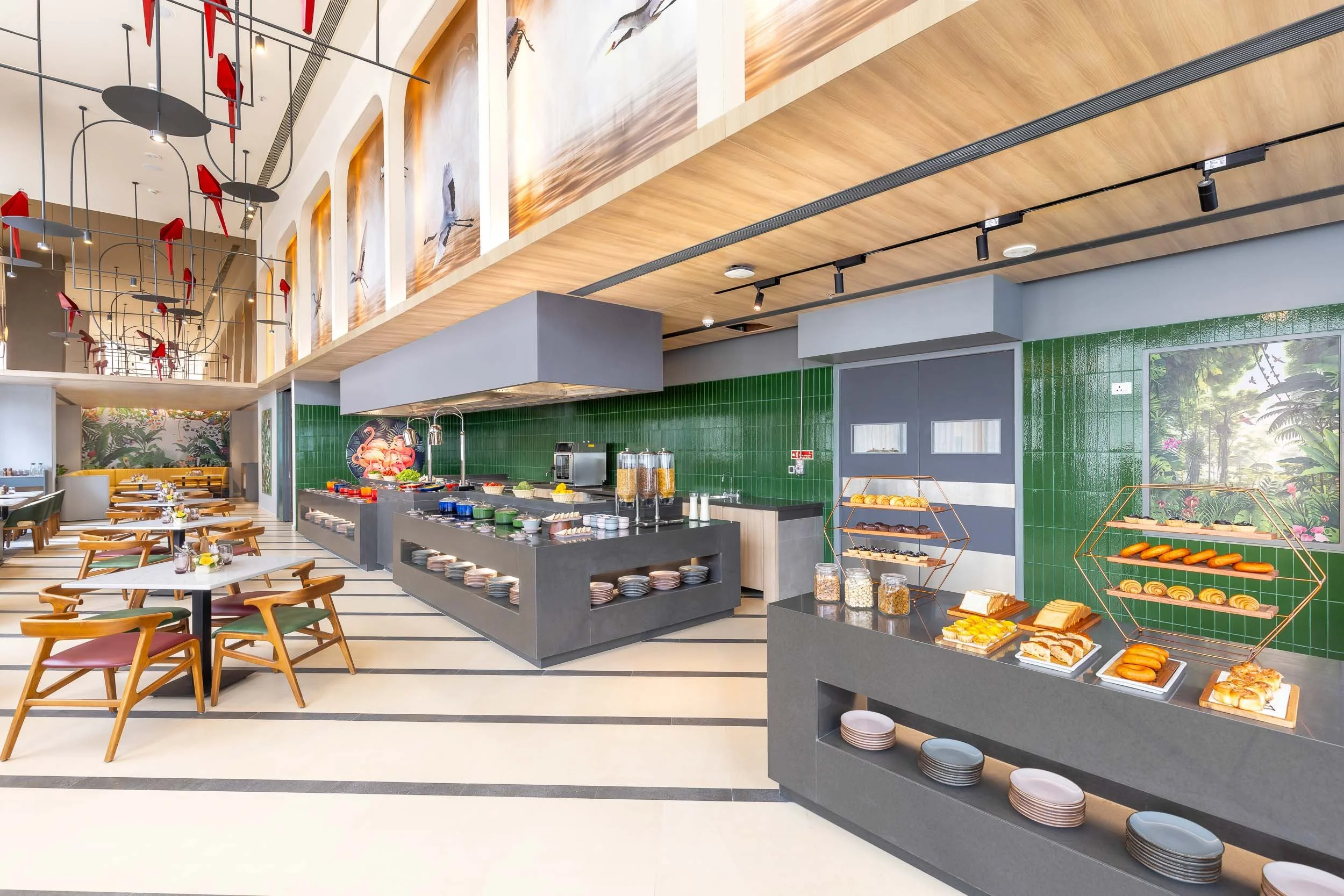 Interior photography of a modern hotel breakfast buffet area featuring a long serving counter, green tile accents, food display stations, and a custom slatted wood ceiling