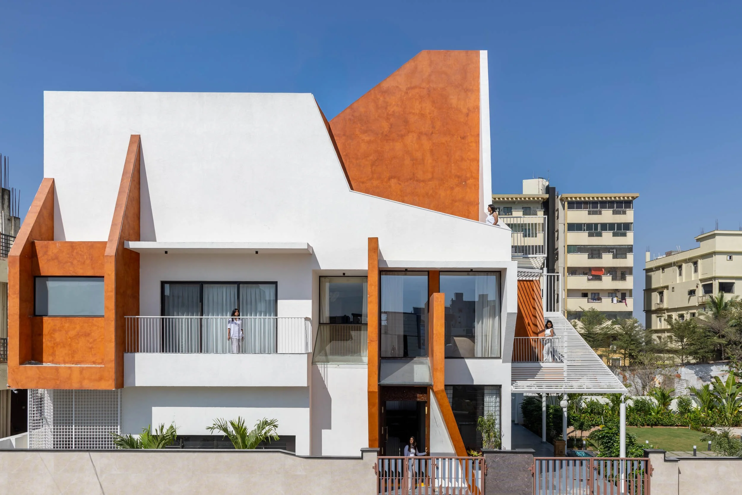 Professional wide-angle exterior architectural photography of a modern residential home, highlighting its geometric white and terracotta design within its neighborhood context.