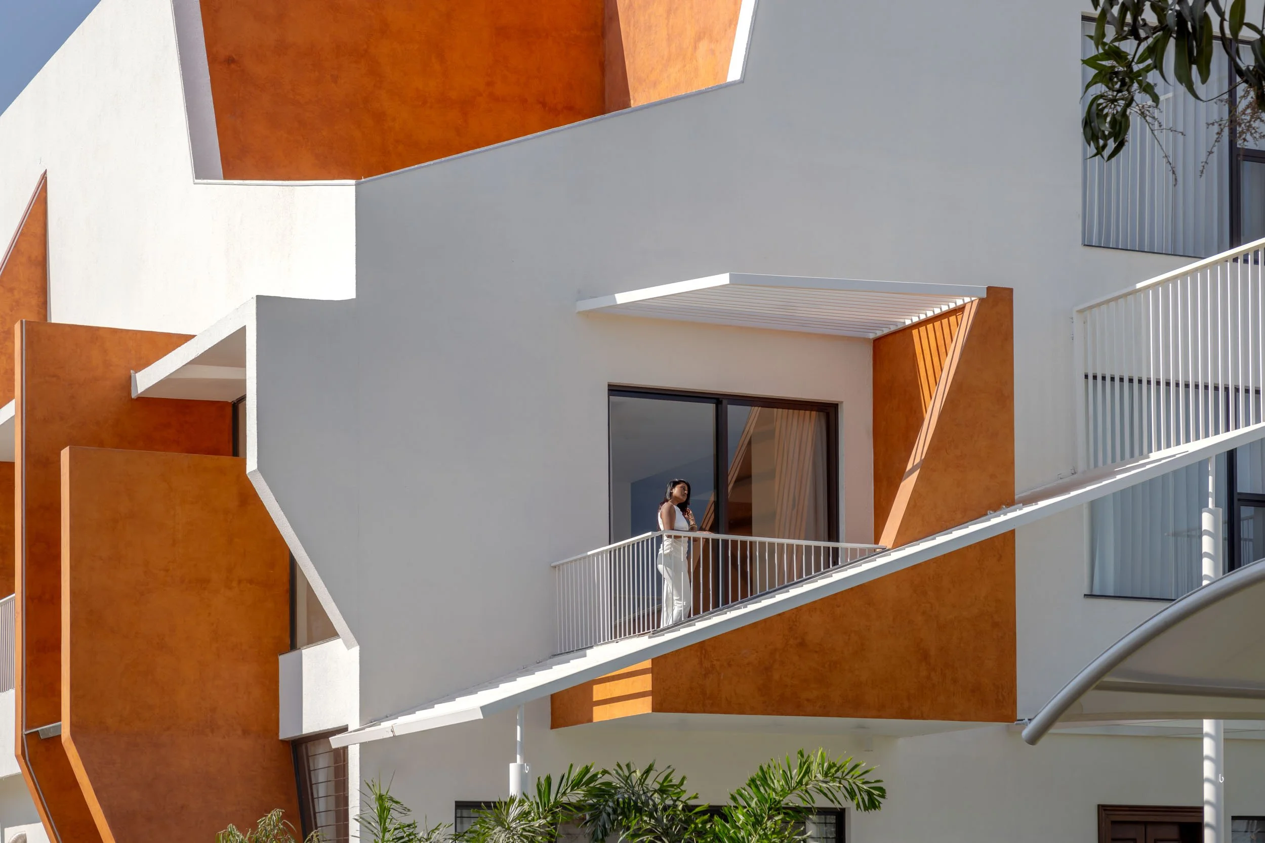 Professional exterior architectural photography of a modern residential home featuring striking geometric forms and vibrant terracotta accents