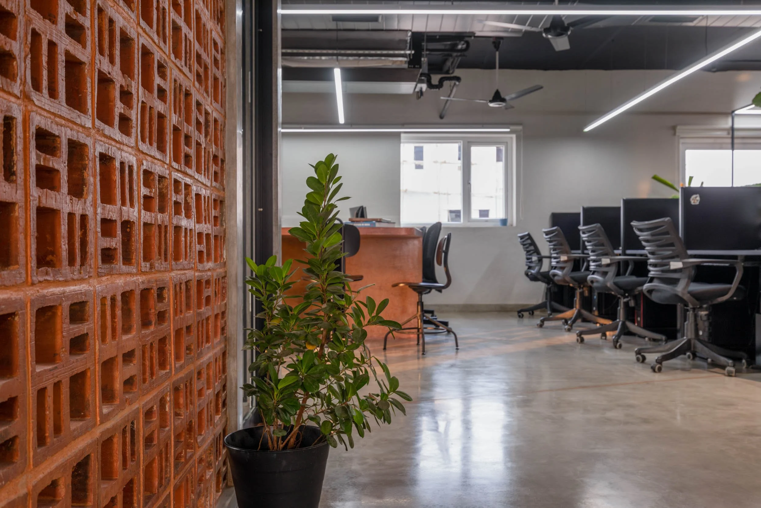 Commercial interior photography showcasing an industrial-style corporate workspace, highlighting decorative brickwork, open-plan desk arrangements, and concrete flooring
