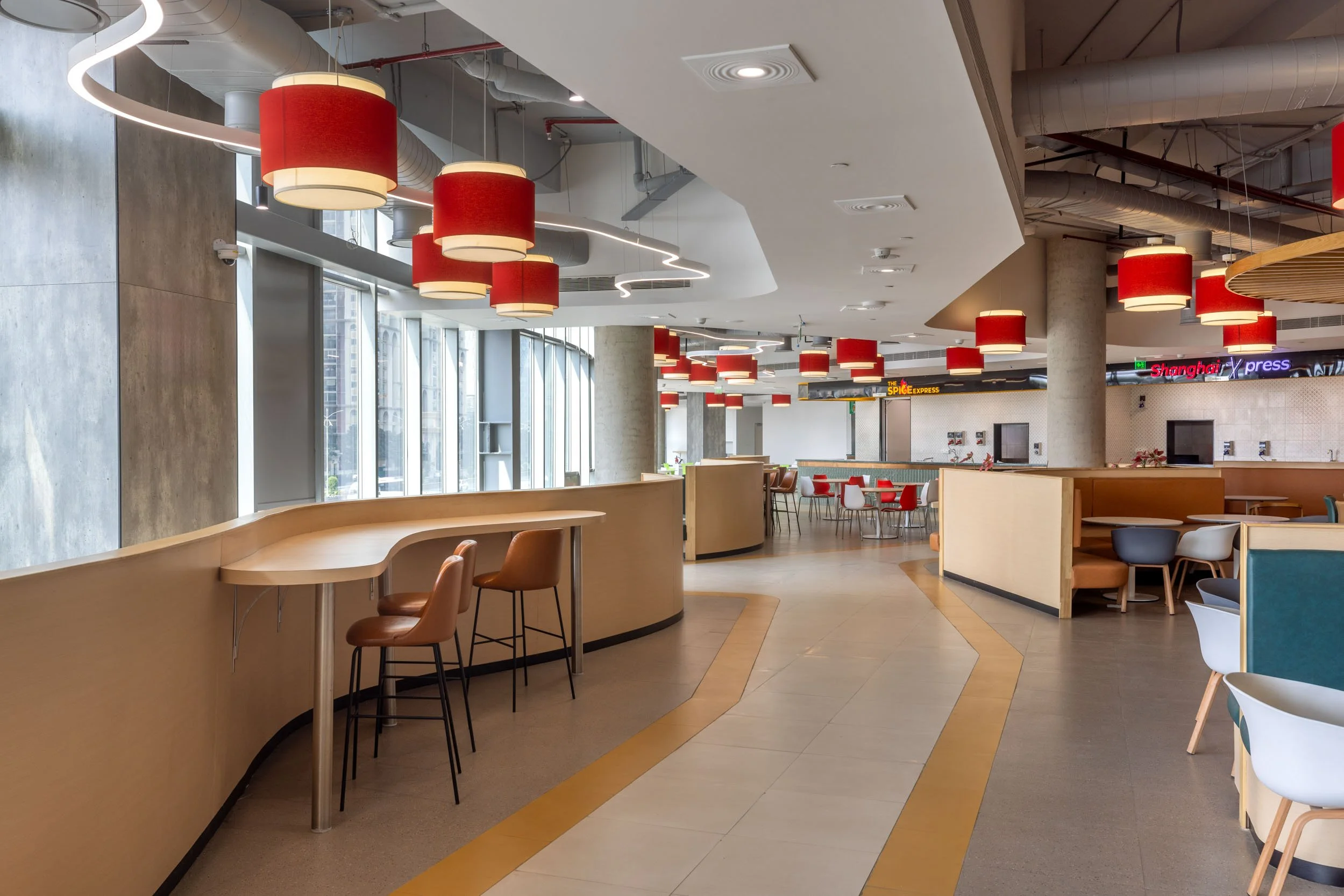 Commercial interior photography showcasing a modern cafeteria design, highlighting custom lighting fixtures, exposed ceiling architecture, and vibrant contemporary hospitality interiors."