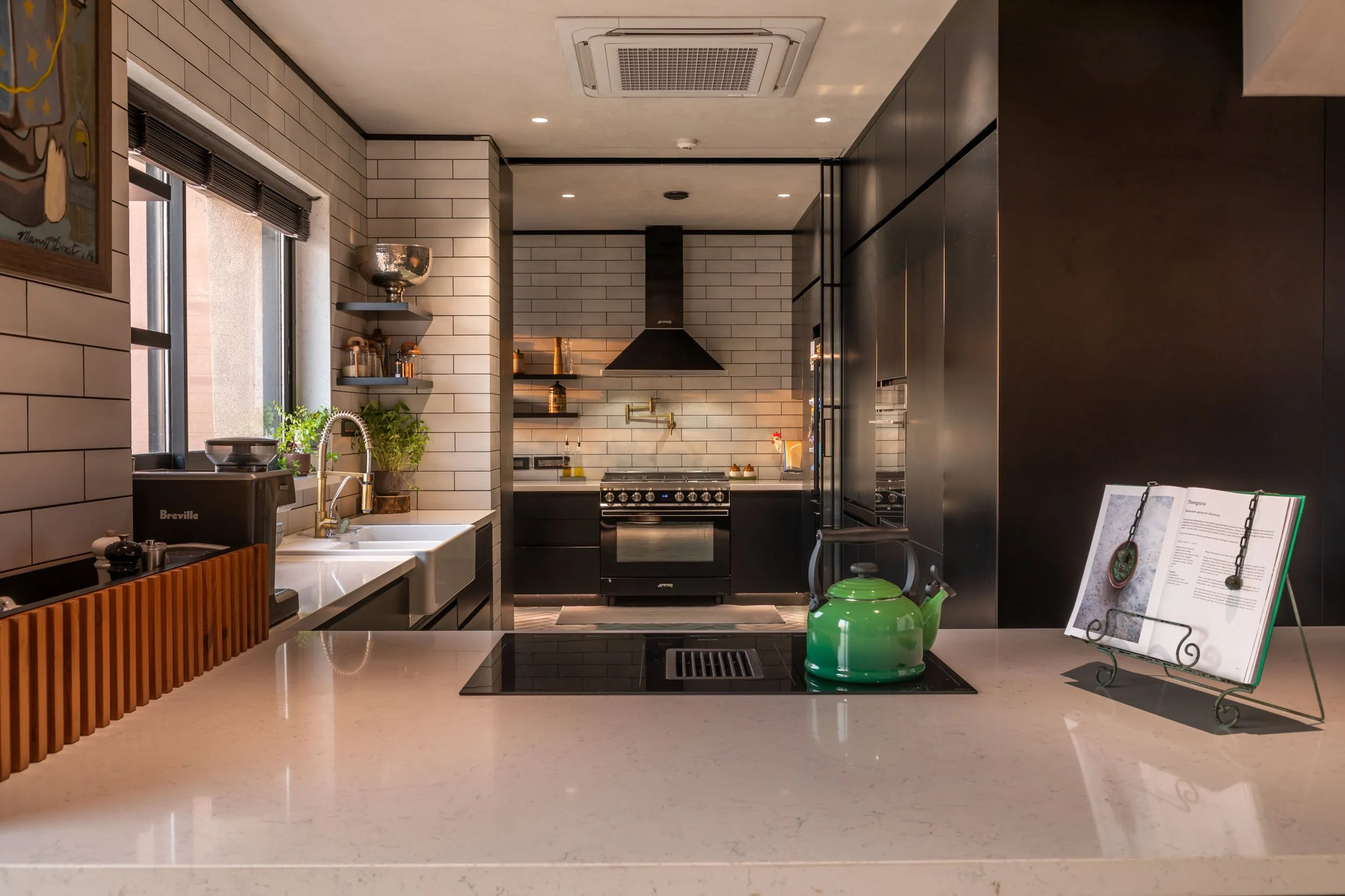 Modern residential kitchen featuring dark cabinetry, bright countertops, and warm architectural lighting