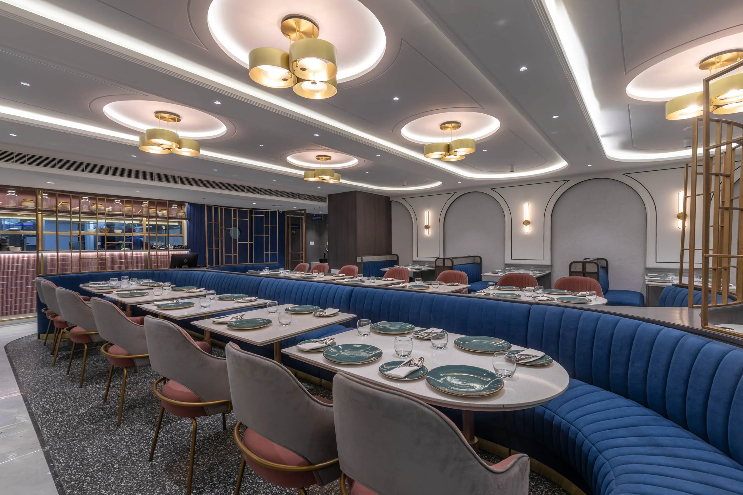 Commercial interior photography showcasing a luxury hospitality dining space, highlighting custom blue booth seating, intricate ceiling architecture, and elegant restaurant interior design