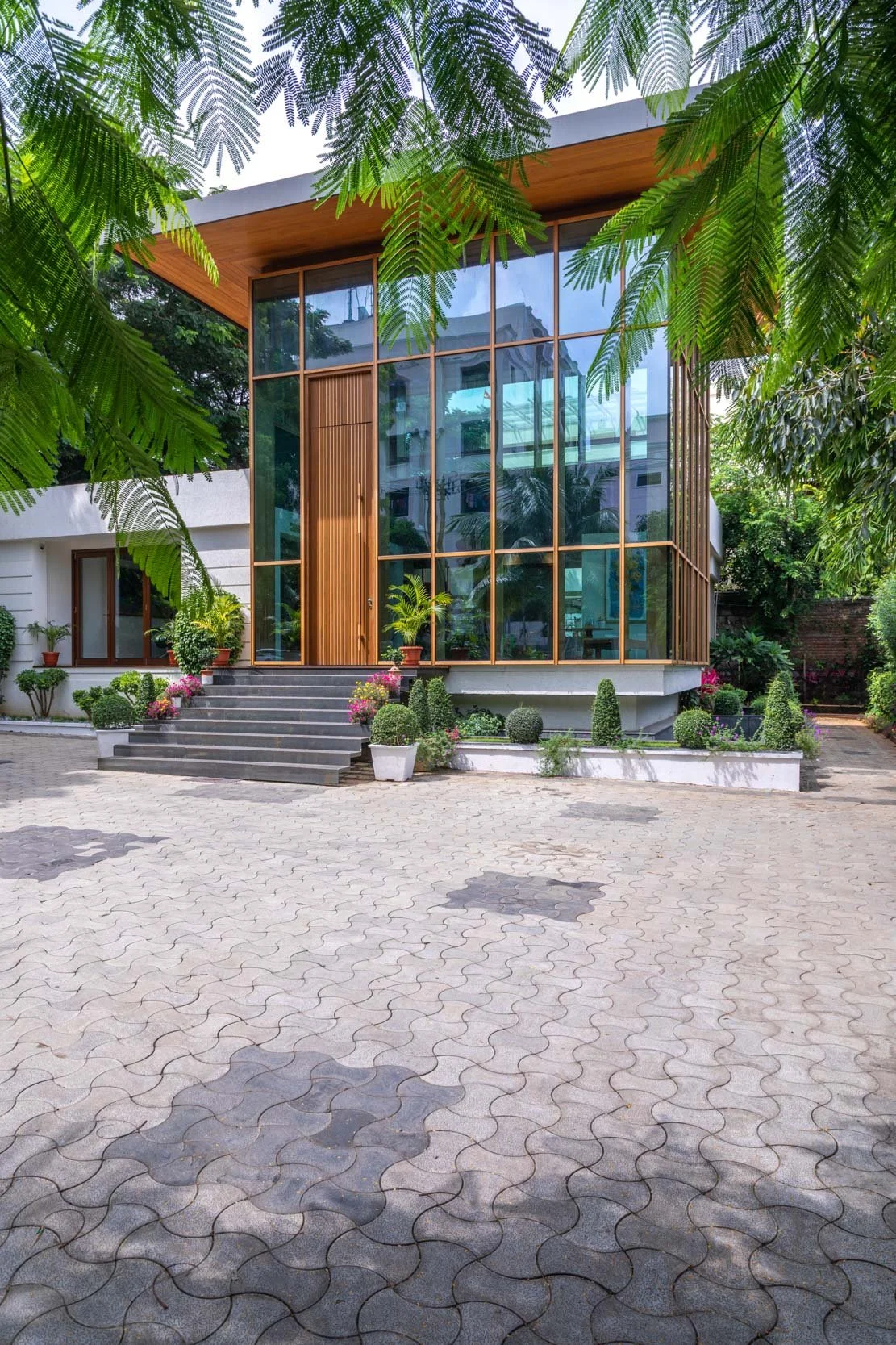 Professional interior architecture photography capturing a bright and spacious modern lounge, highlighting expansive glass windows, warm wooden architectural details, and a seamless indoor-outdoor connection