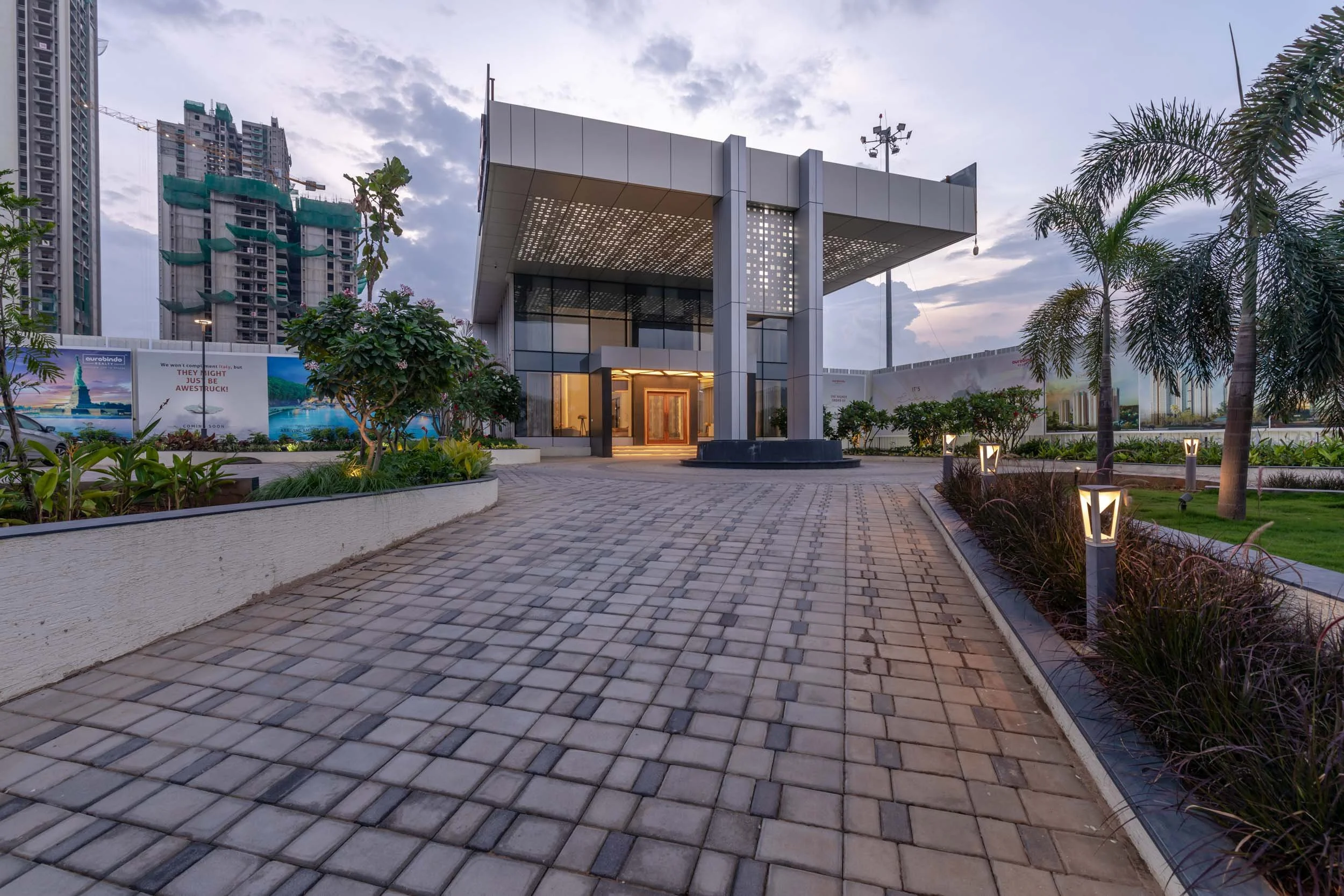 Exterior commercial architecture photography capturing a modern corporate building entrance with a spacious paved approach, sleek facades, and a striking twilight sky.