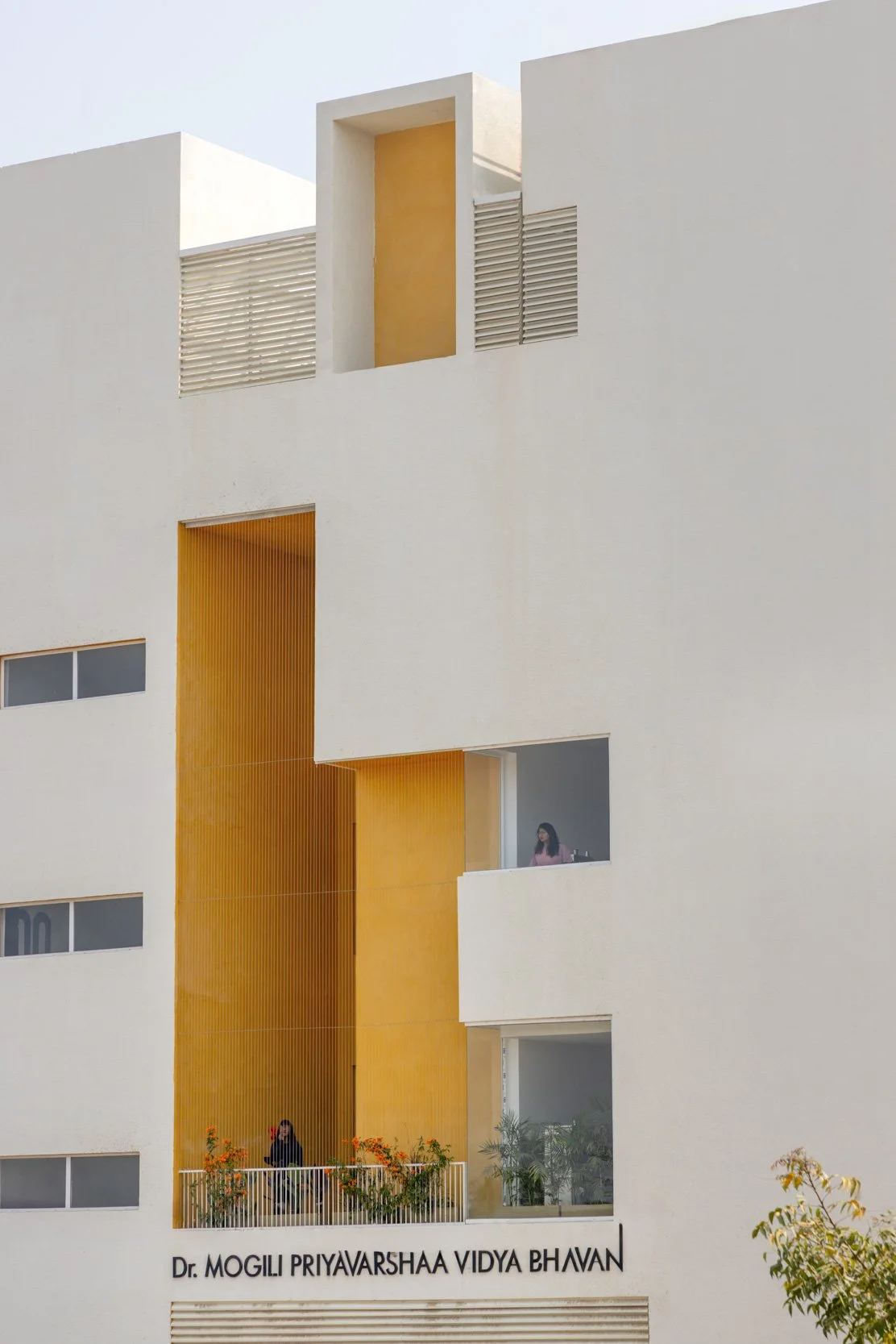 Professional exterior architectural photography capturing a modern multi-level building facade, highlighting a unique geometric design with clean white framing and warm architectural accents
